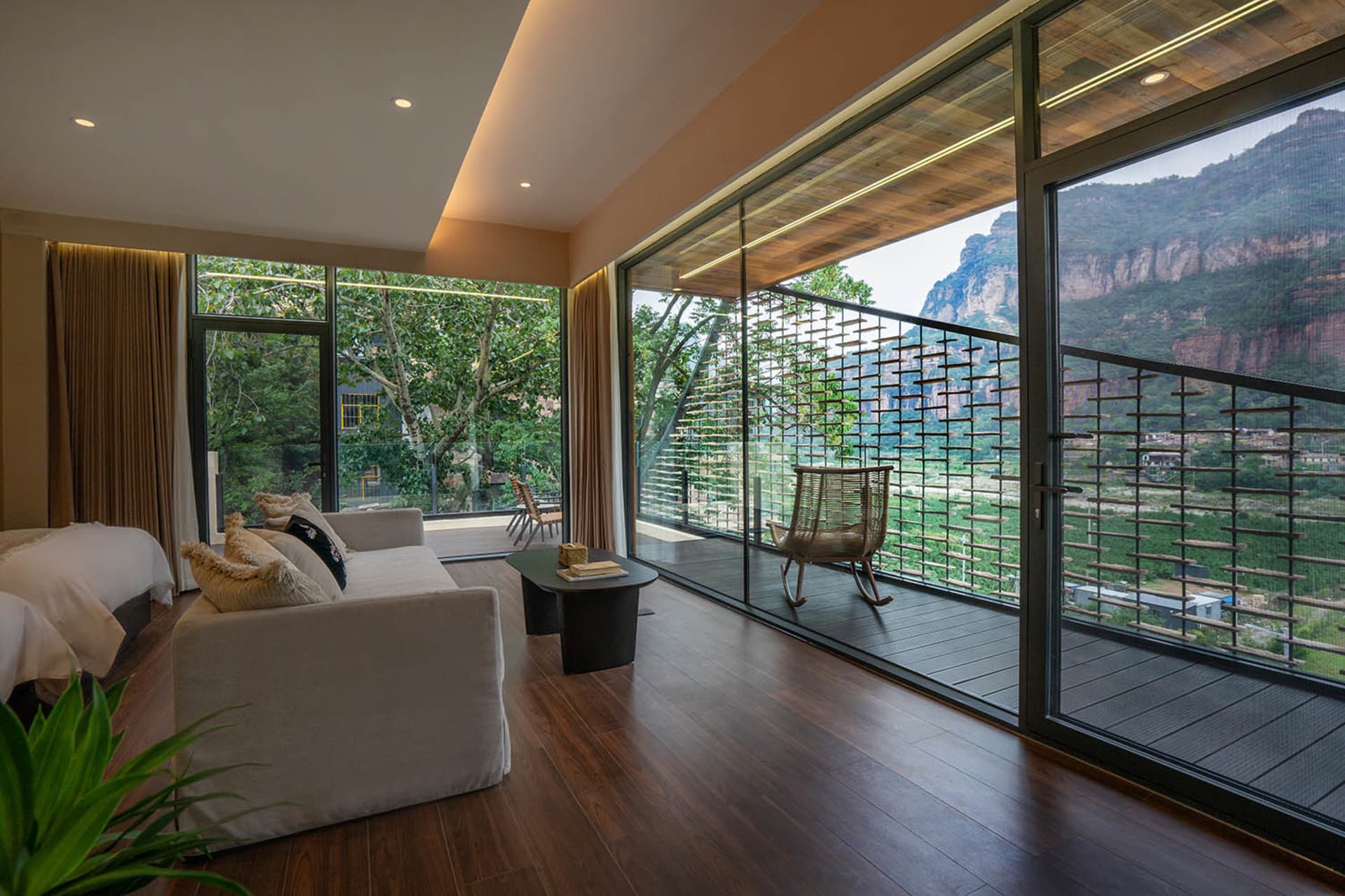 A well-lit living room with wooden floors, a couch, chair, and dining table, featuring a large window for natural light