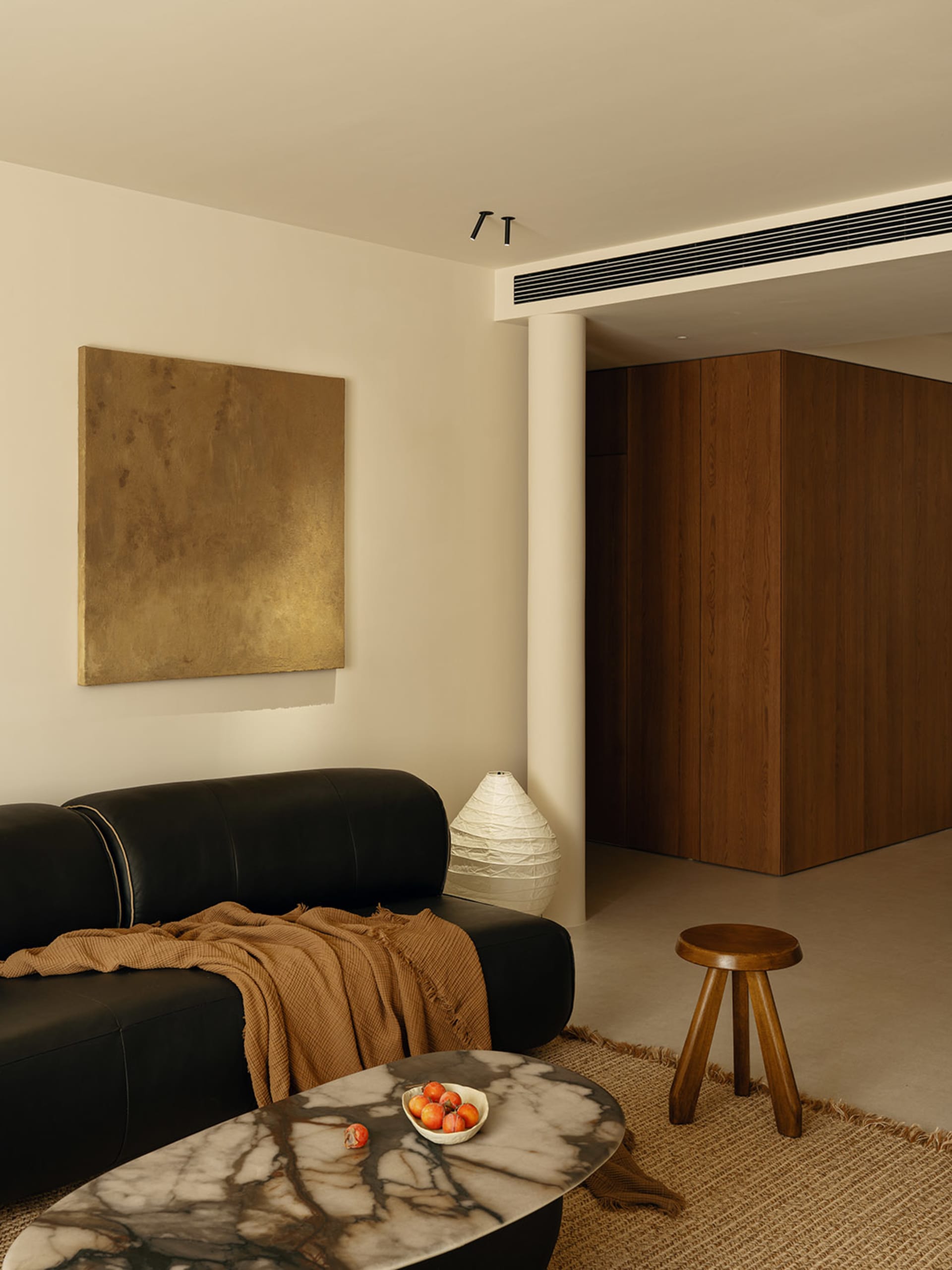 Cozy living room with a black couch, chair, and dining table, featuring a white wall, brown wooden door, and decorative elements