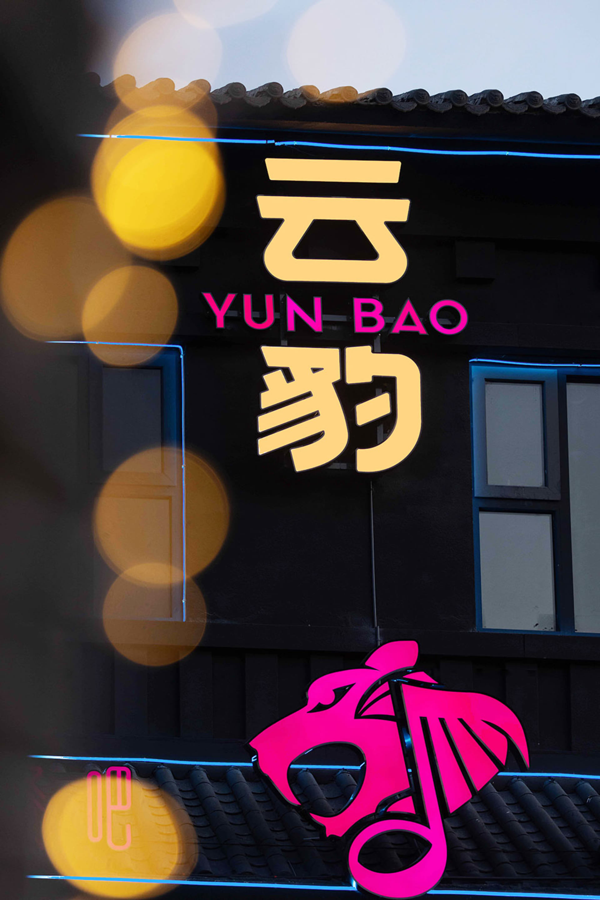 A black building with a pink sign written in a foreign language, set in a foreign city or town with unique architecture