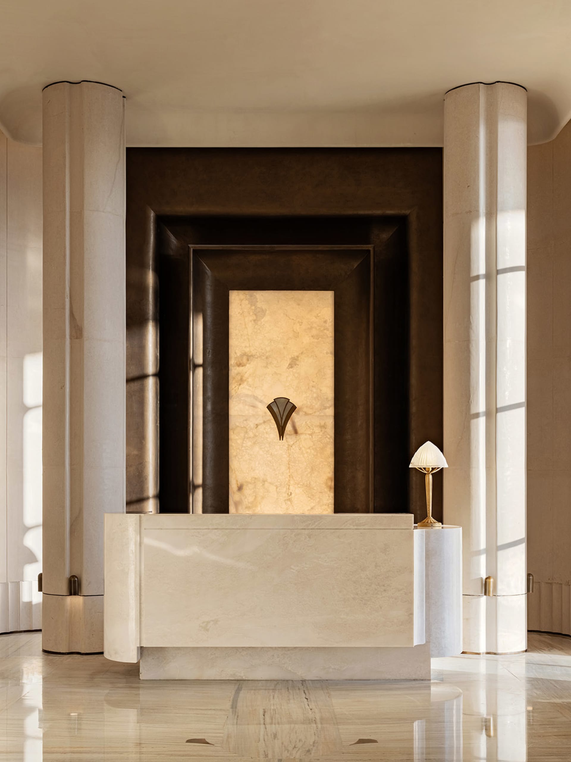 A modern bathroom with a white marble countertop, a gold lamp, and a sink and mirror, creating a luxurious and elegant space