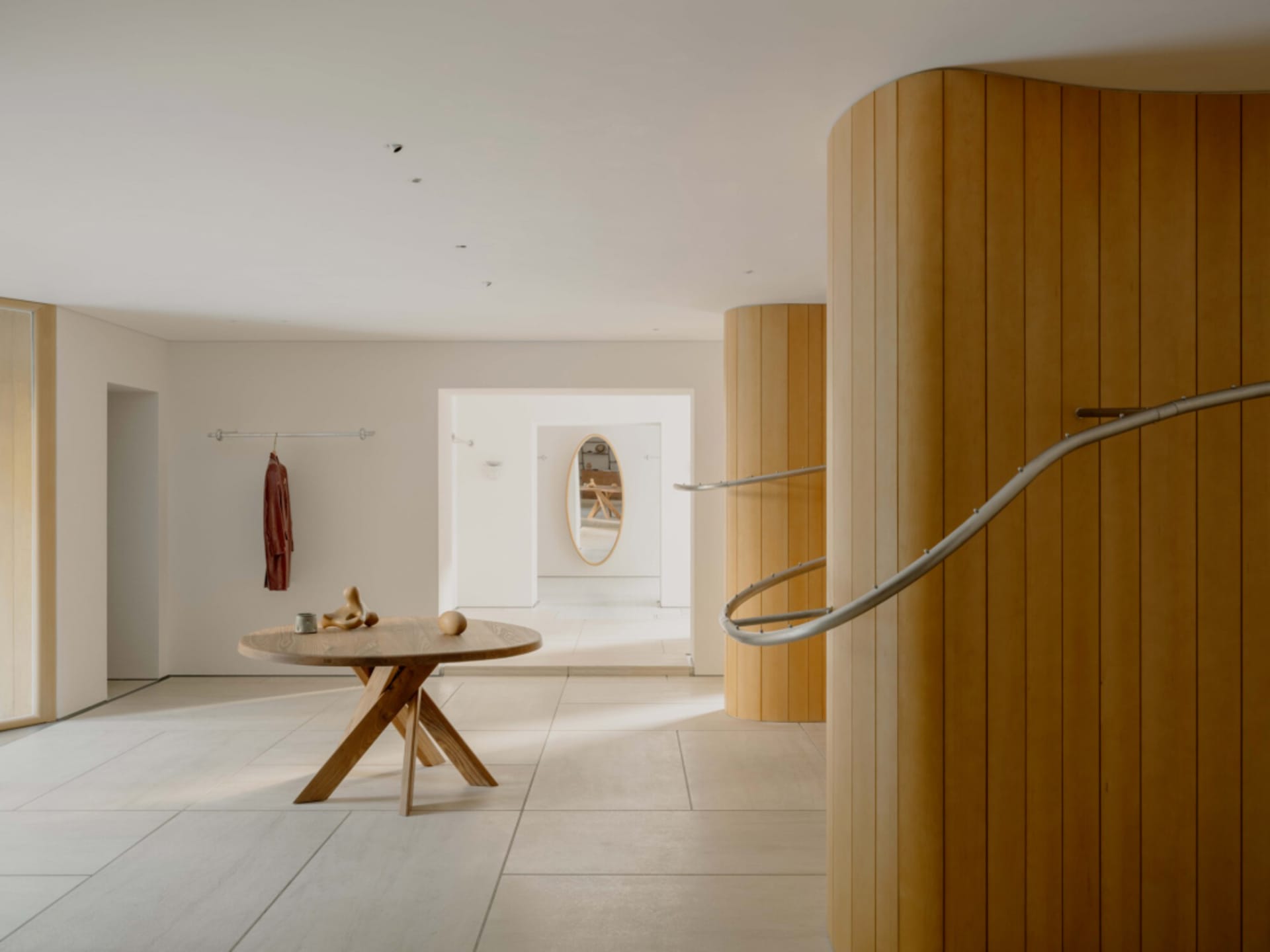 A warm and cozy room with a wooden floor, white wall, and wooden staircase and table, featuring a mix of natural and artificial lighting