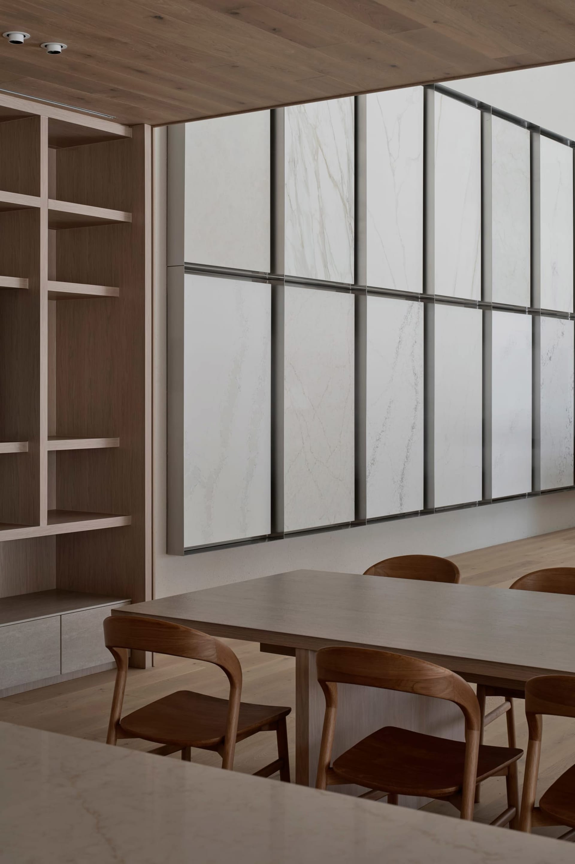 Dining room with a wooden floor, a wooden table, and chairs, surrounded by a bench, with a dimly lit atmosphere and a marble-like wall texture