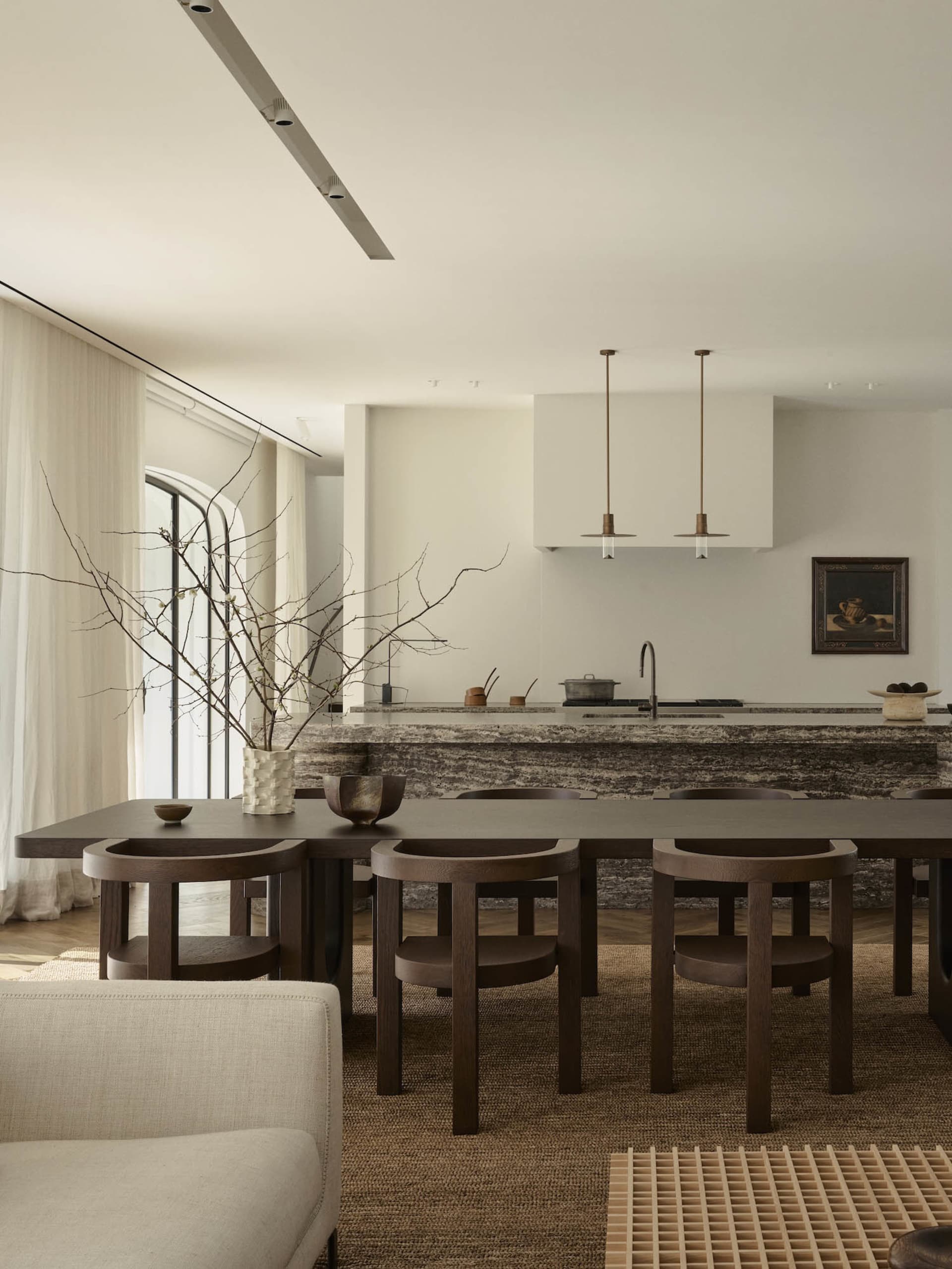 Modern kitchen with a marble countertop, wooden floor, and natural light from windows, featuring a center island and dining area