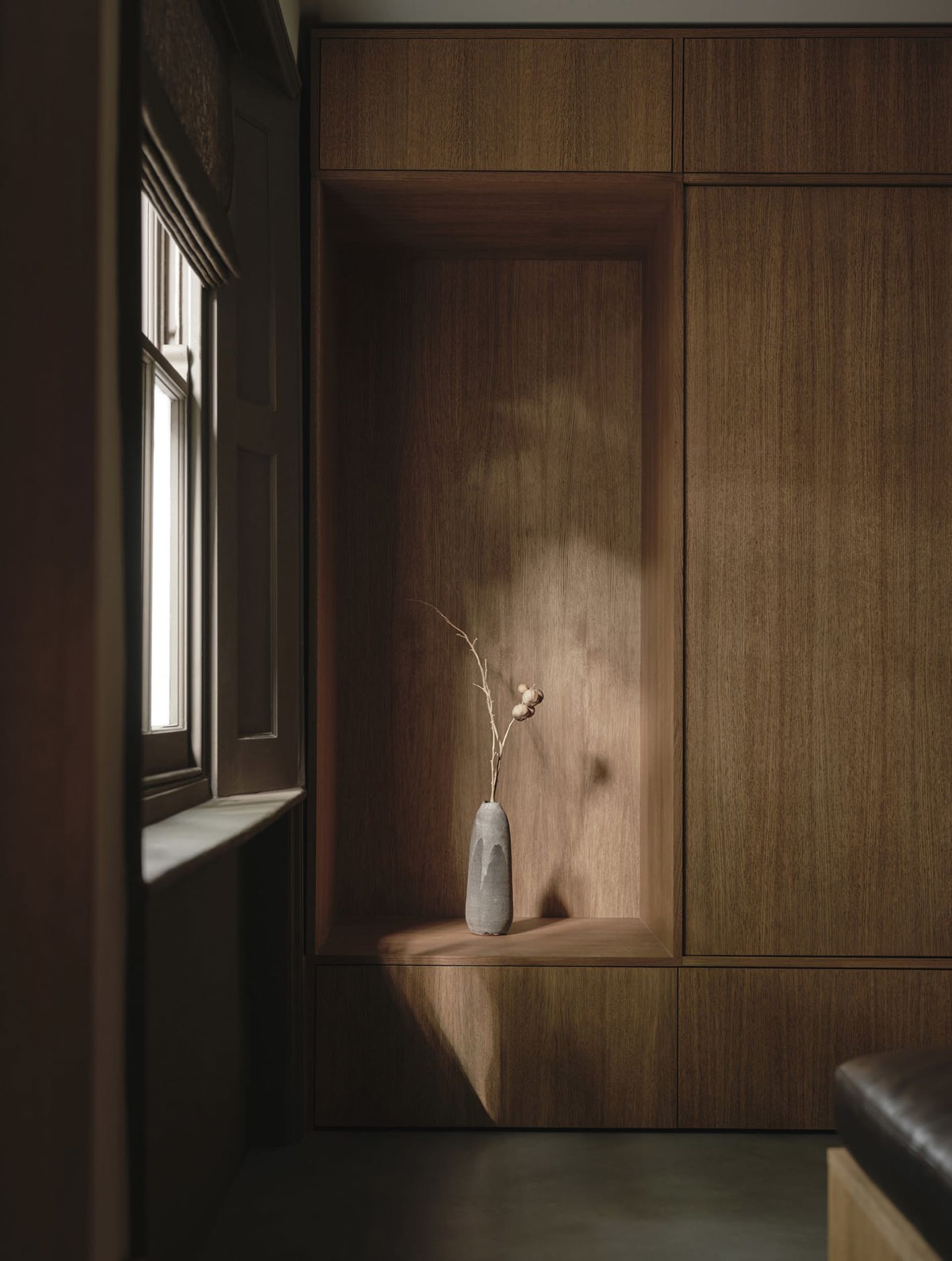 A dimly lit room with a wooden cabinet and a vase holding a flower, creating a calm and serene atmosphere