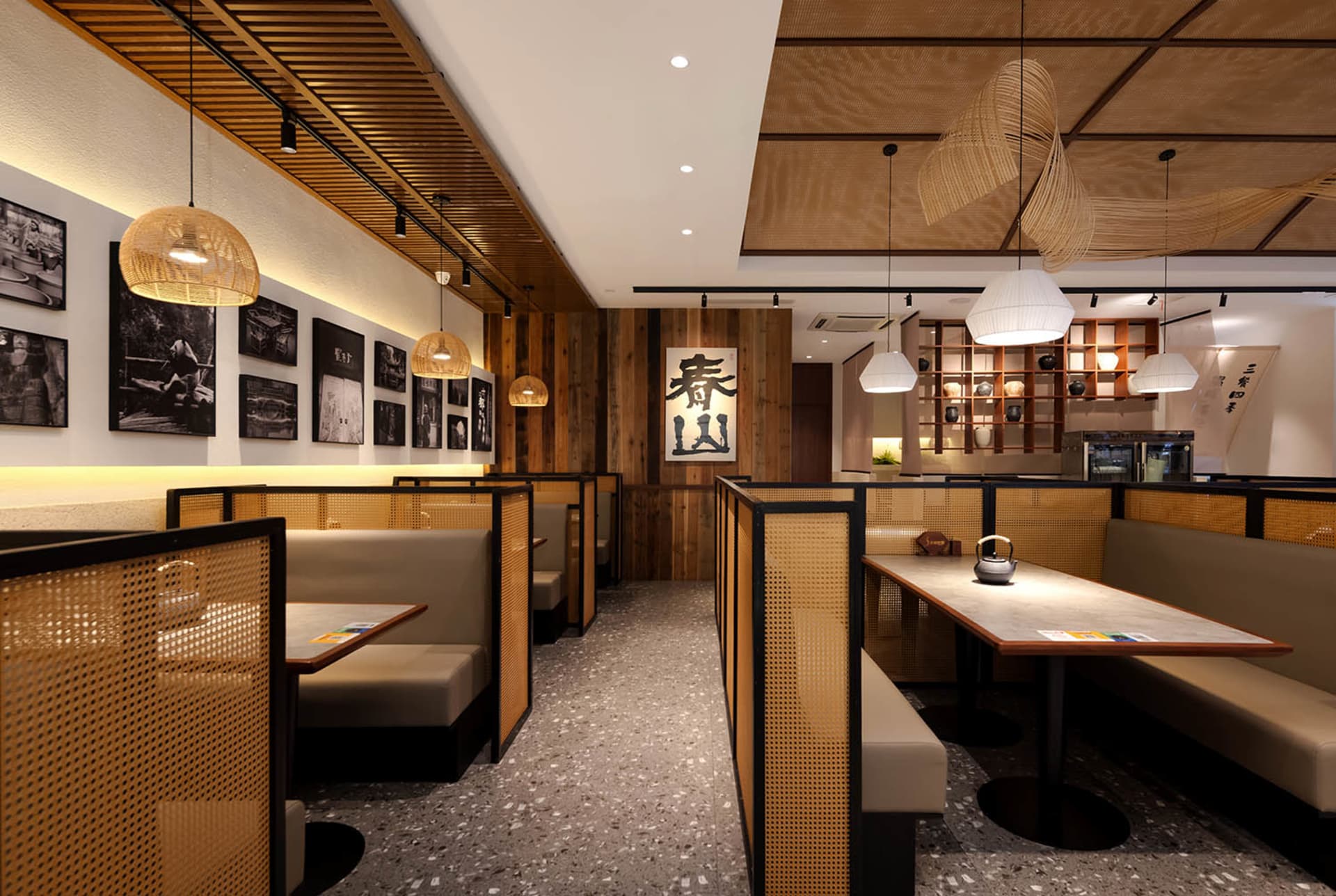Cozy restaurant with wooden floor, booths, and tables, featuring a mix of wood and metal elements, with dim lighting and potted plants