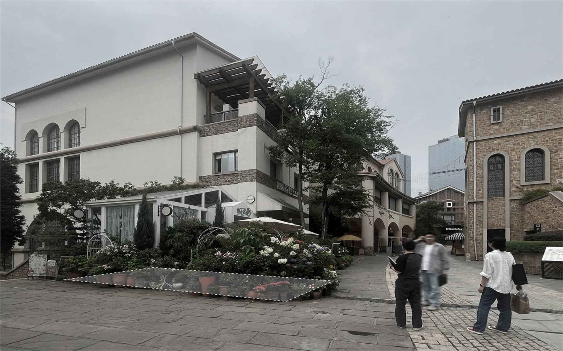 一張石牆建築物照片，附有鐘錶，設置在一條街上，附近有個人