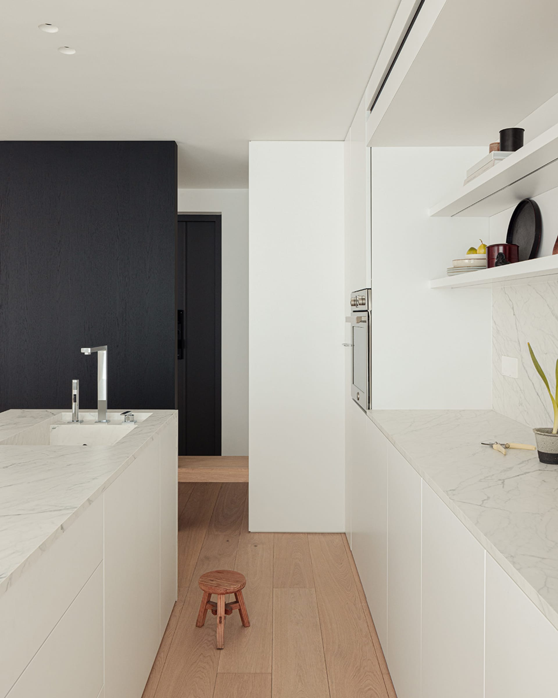 Modern kitchen with wooden floors, white cabinets, and natural light from windows