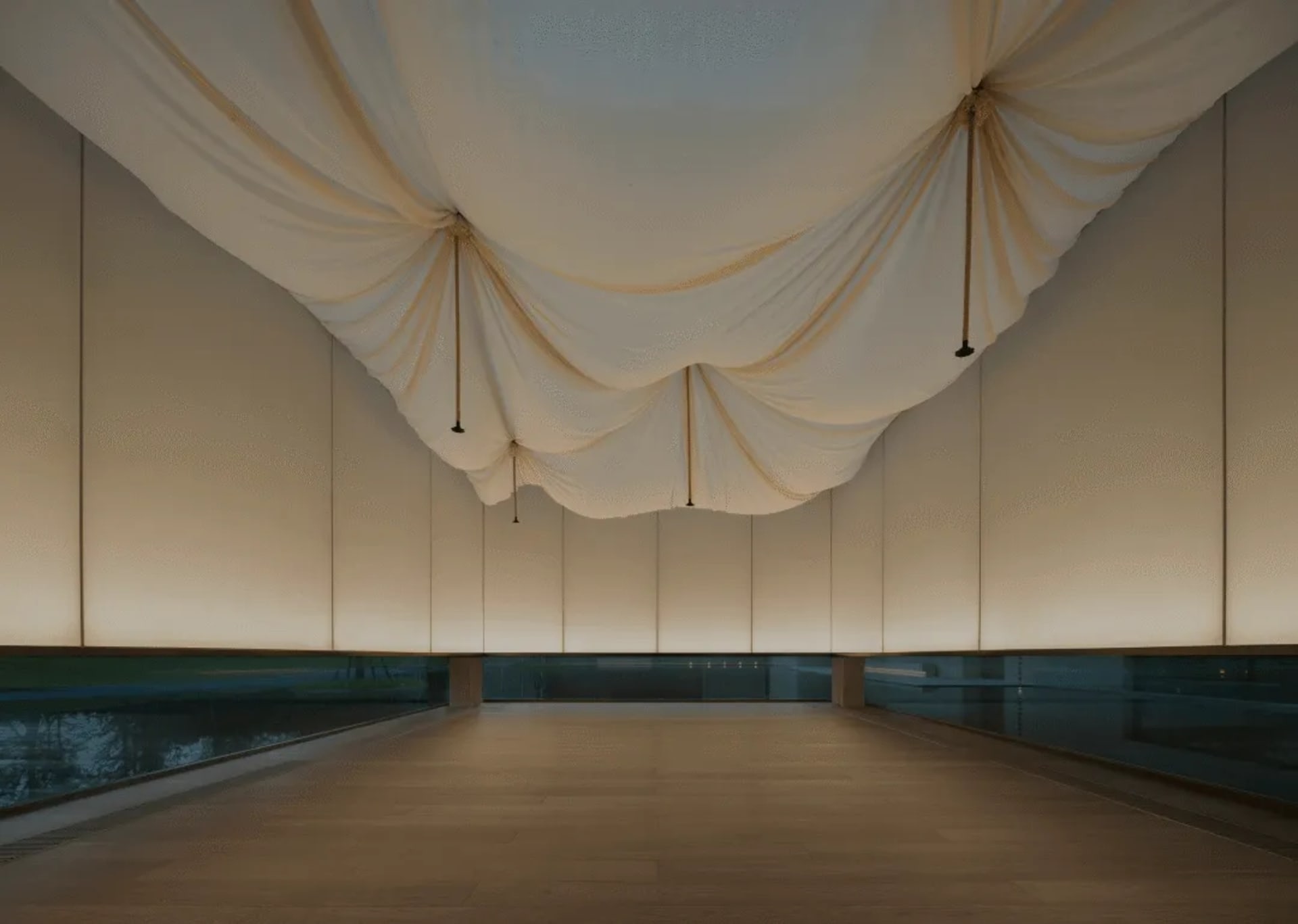 A large, empty lobby with white walls covered in fabric, a white floor, and a white ceiling, giving a clean and modern appearance