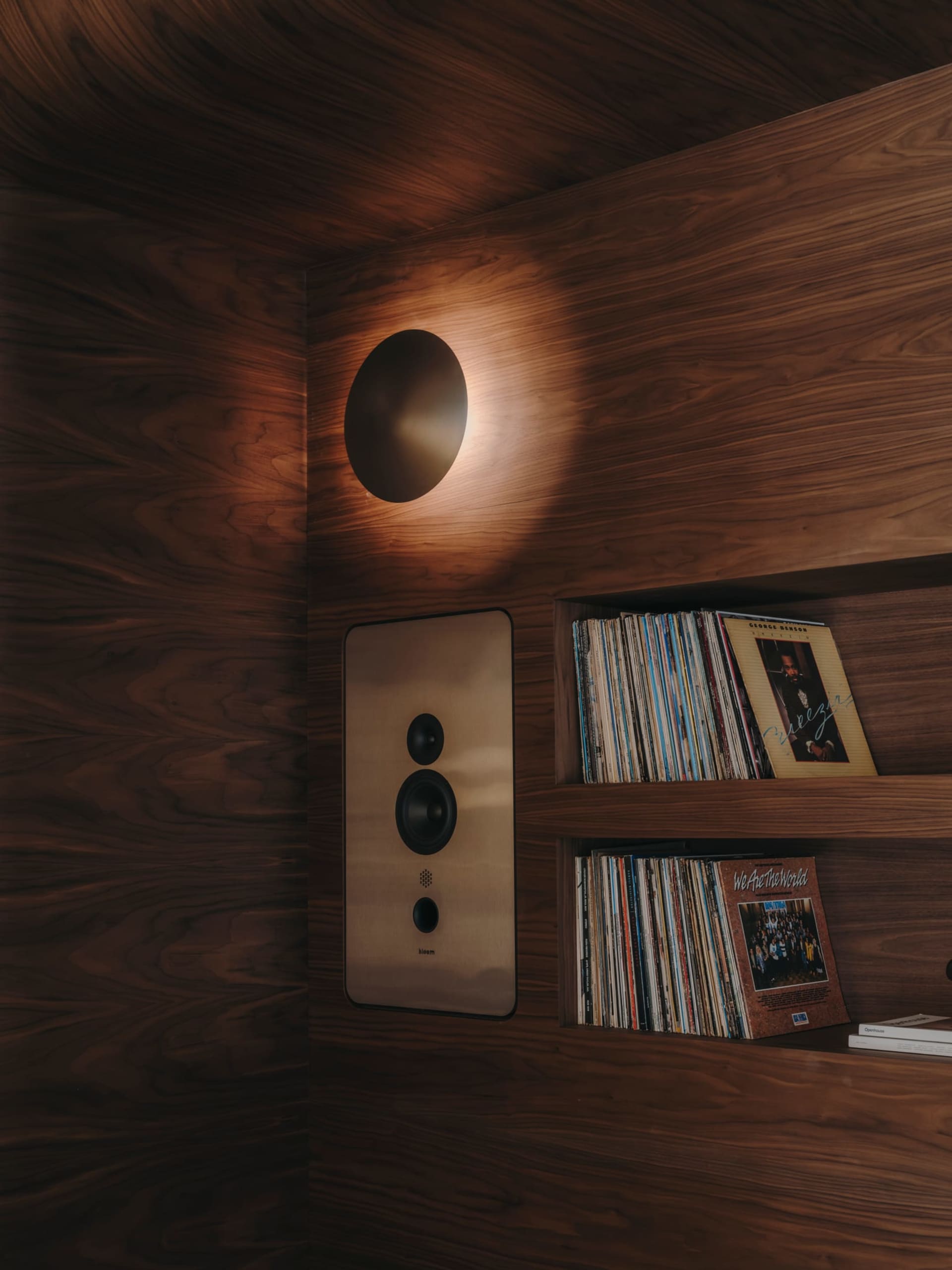 Cozy living space with wooden walls, a wooden bookshelf, and a light above it, creating a warm and inviting atmosphere