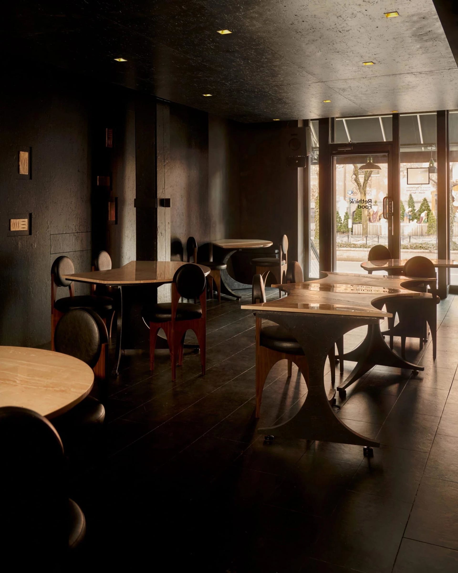 Dimly lit restaurant interior with semi-circular seating area, black and white furniture, and decorative items