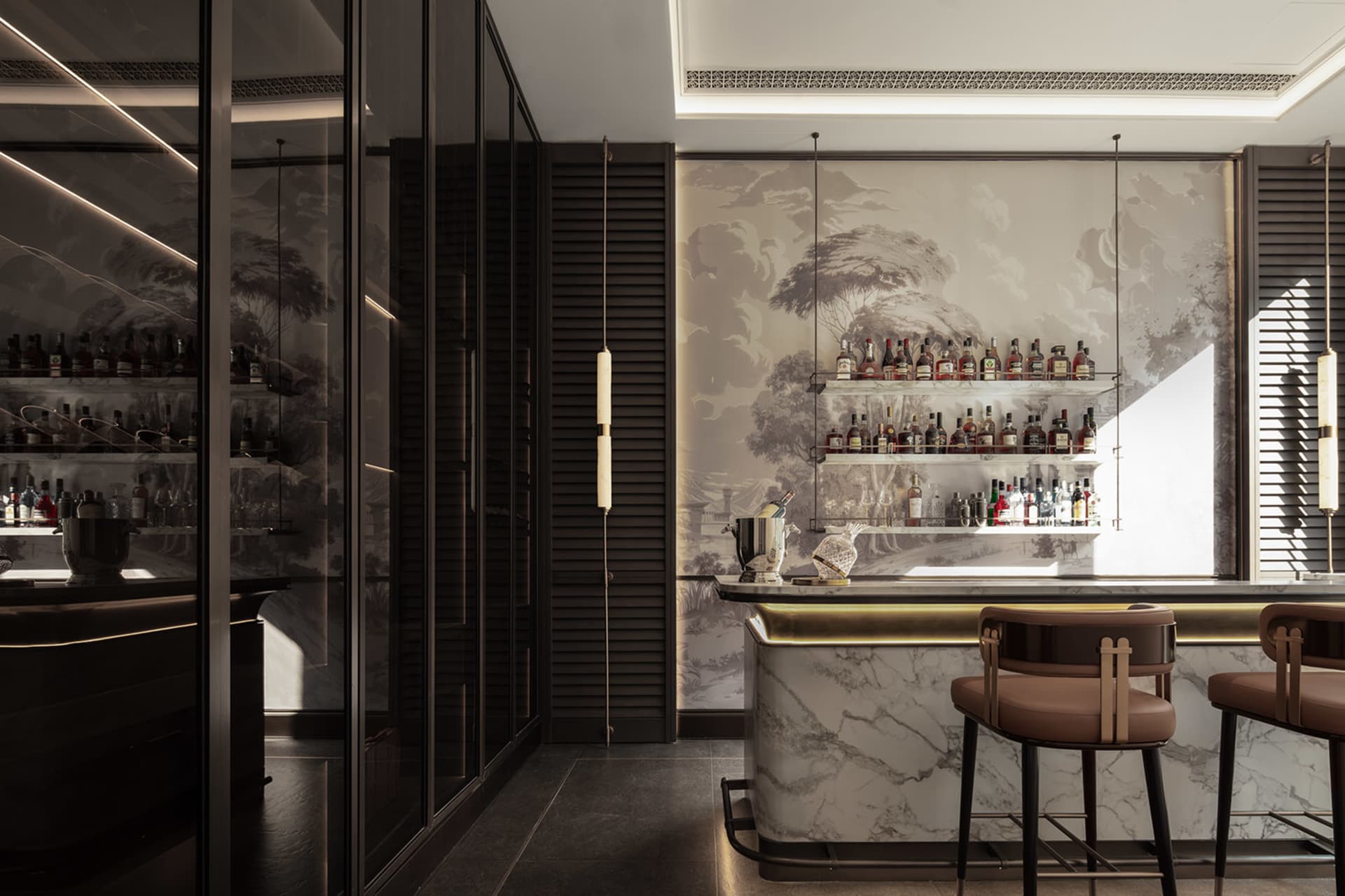 A well-lit bar area with a modern design, featuring a marble countertop, chairs, and a selection of bottles