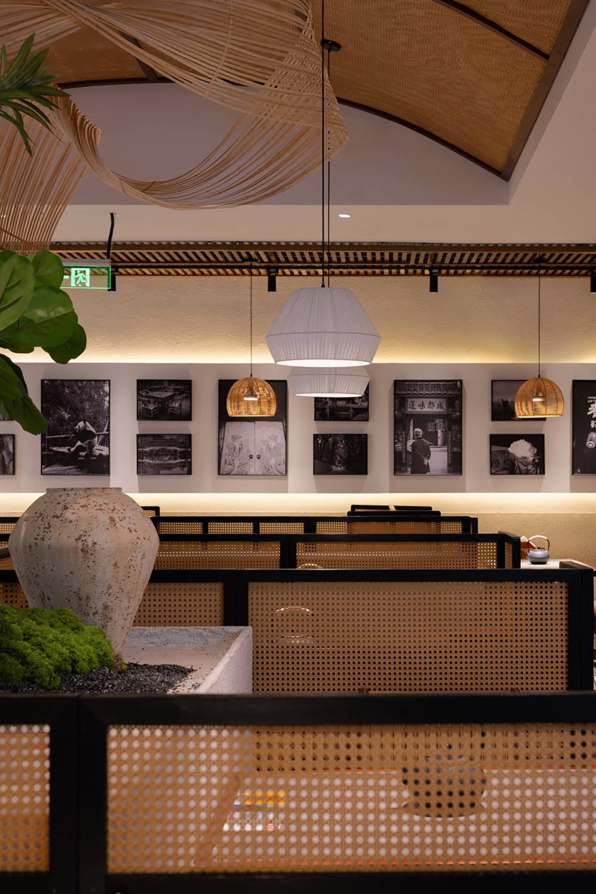 A modern restaurant interior with tables, chairs, artworks, and hanging lights creating a warm and inviting atmosphere