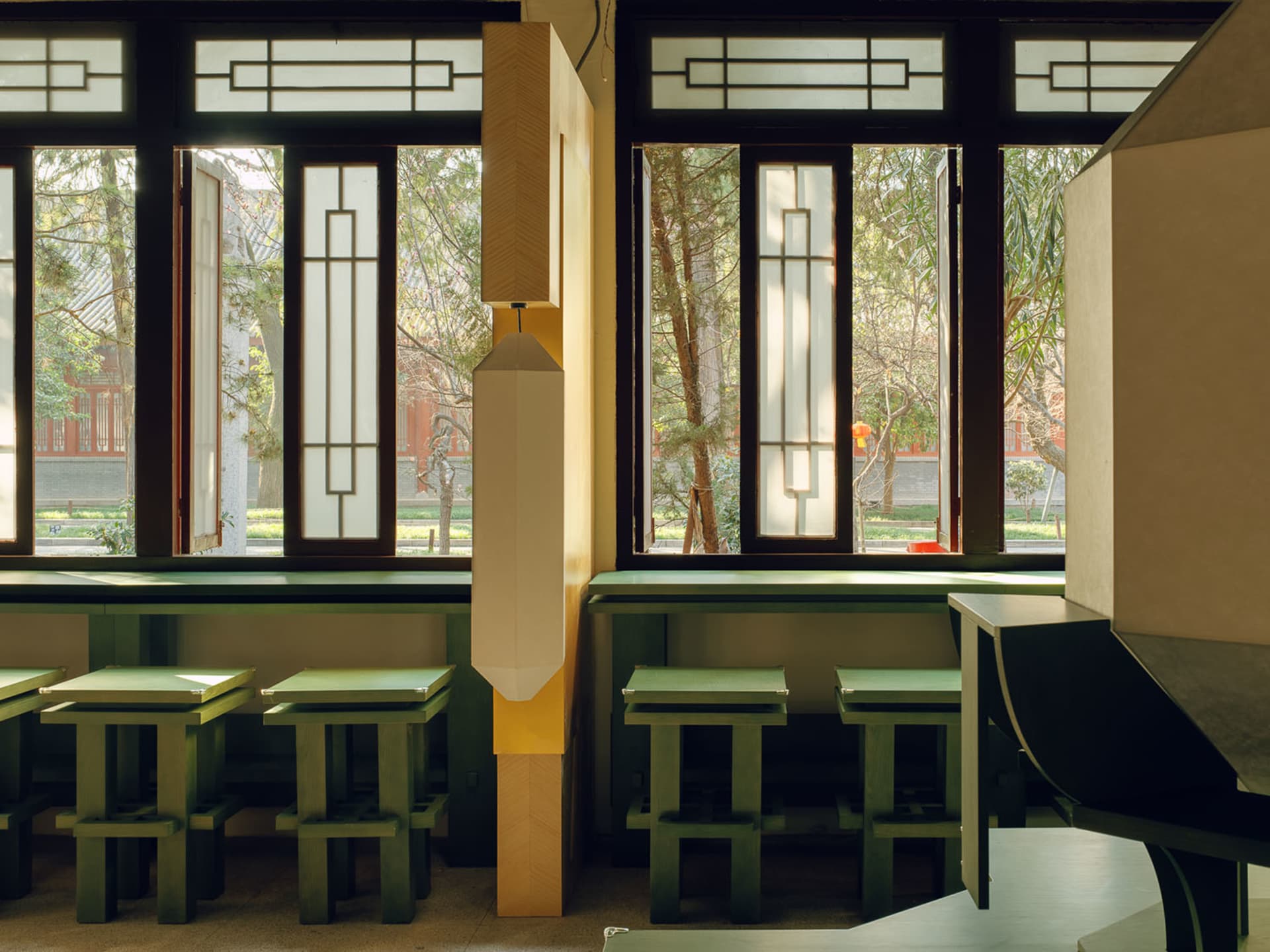 Cozy modern restaurant with green tables, chairs, and accents, natural light, and soft warm lighting