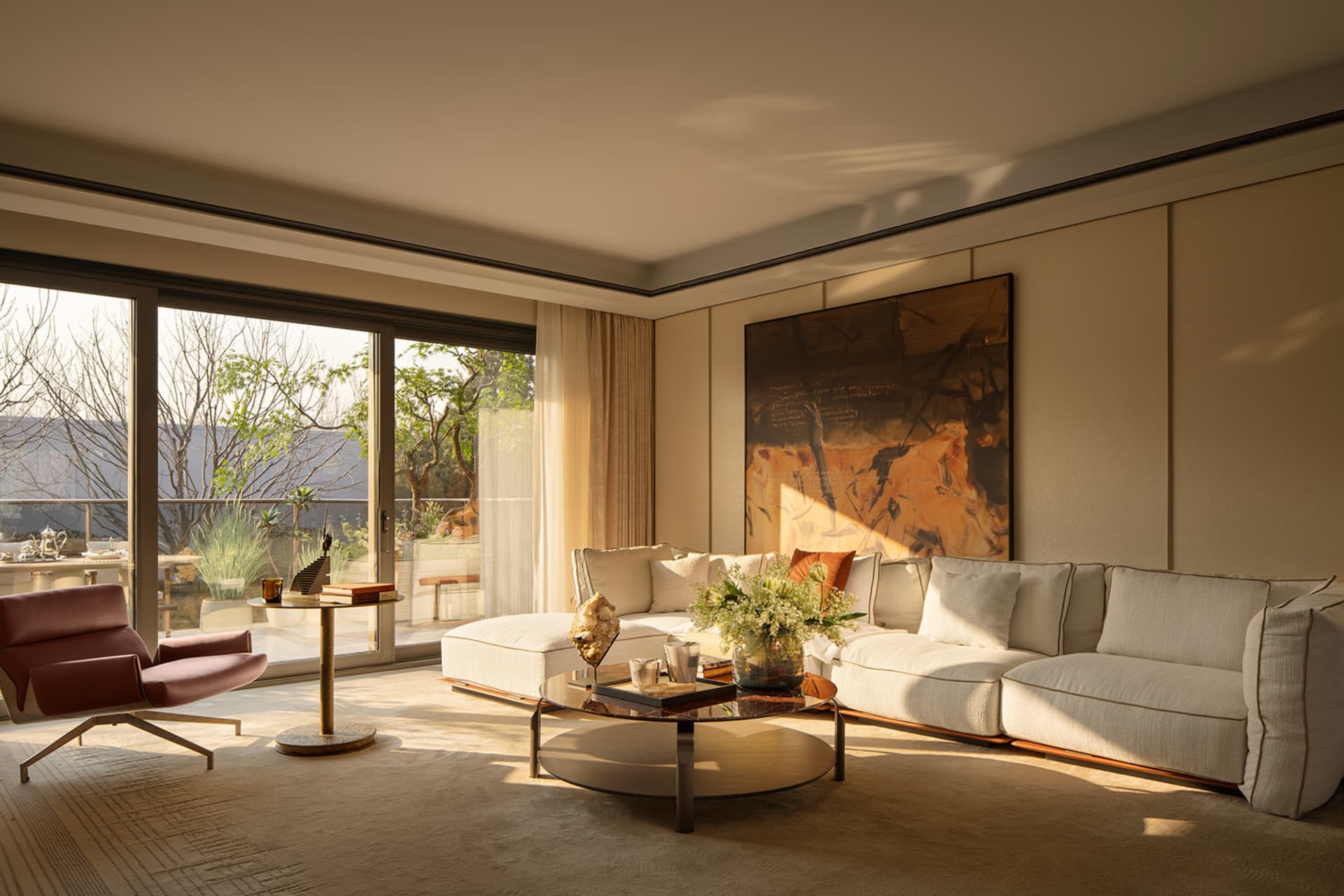 A modern living room with a white couch, a wooden coffee table, and a glass vase, well-lit with natural light from the windows