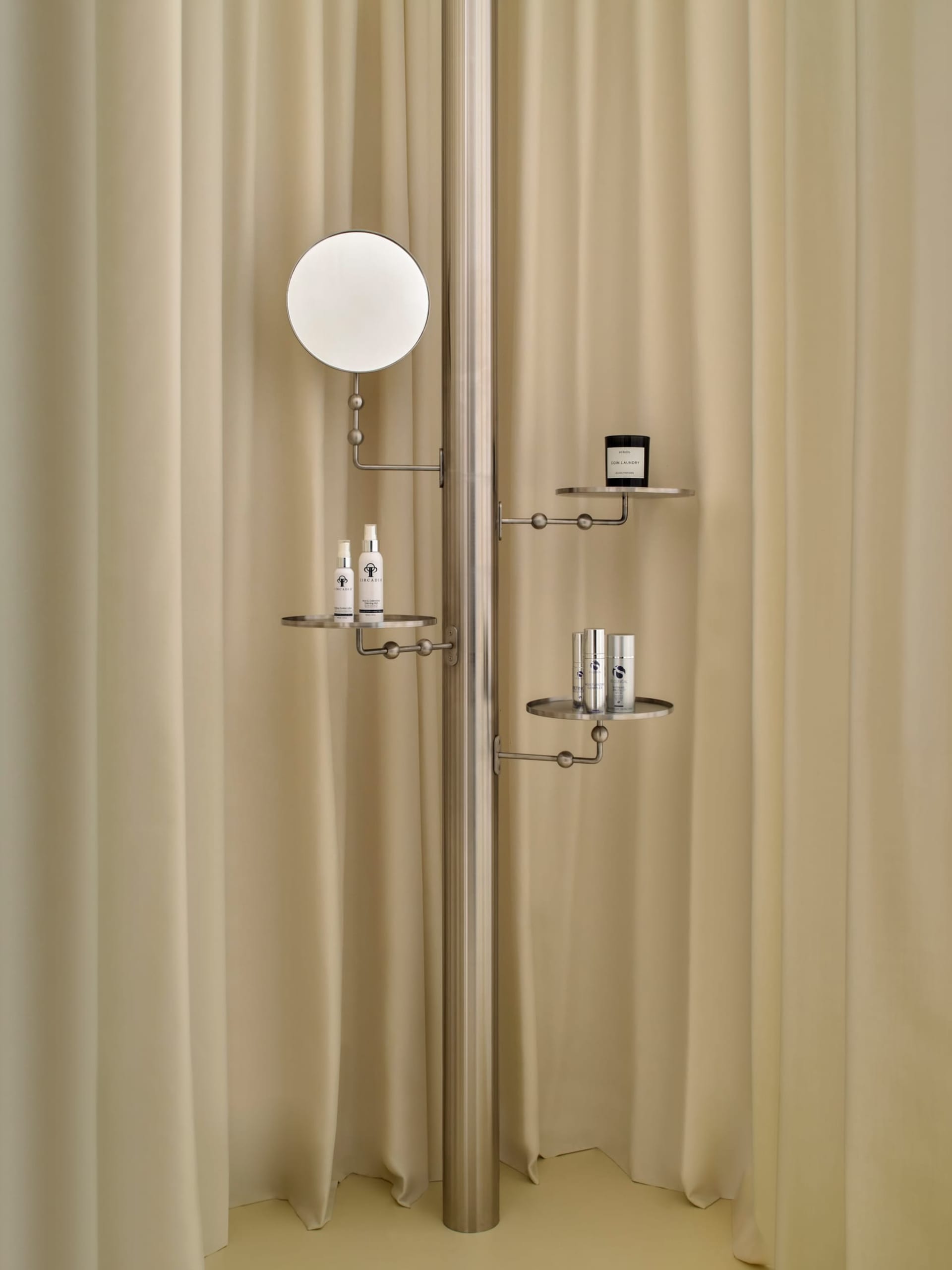 Modern bathroom with a wall-mounted mirror, shelf, and shower curtain, featuring dim lighting and a focus on functionality