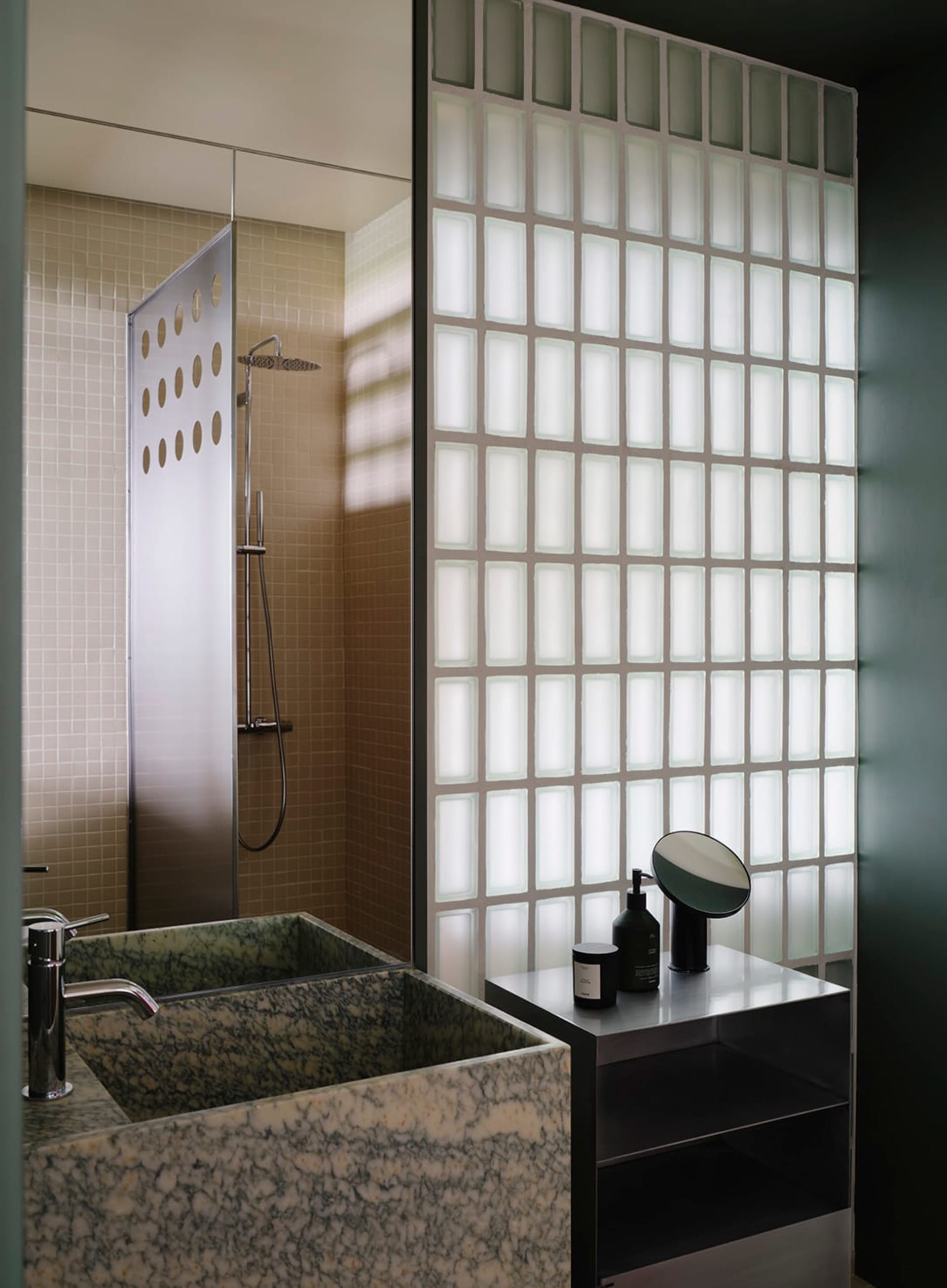 Modern bathroom with a marble sink, a shower, and a mirror above the sink, set against a green color scheme