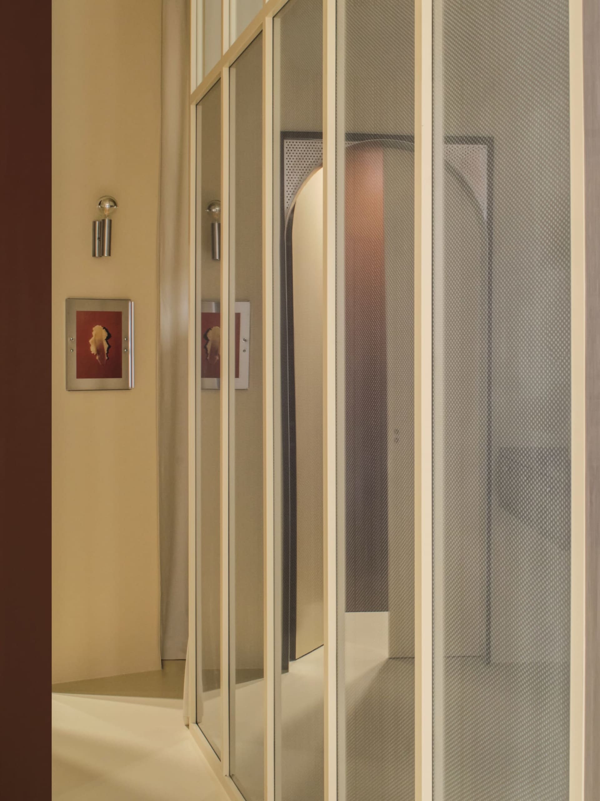 Wooden hallway with a brown color, a doorway, and a mirror, capturing the reflection of the hallway in the mirror with dim lighting