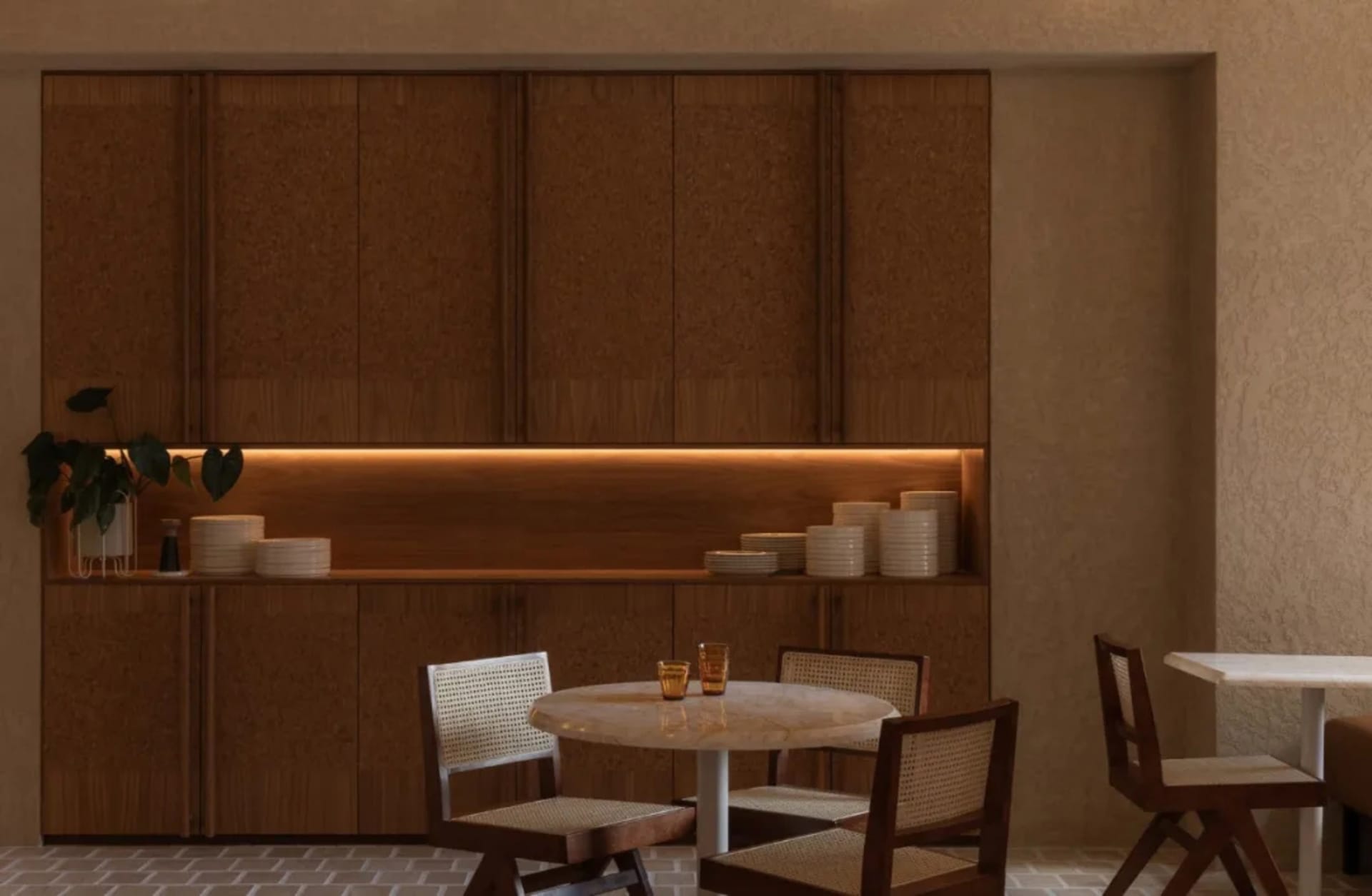 A cozy dining room with a wooden table and chairs, surrounded by cups and bowls, in a warm and intimate atmosphere