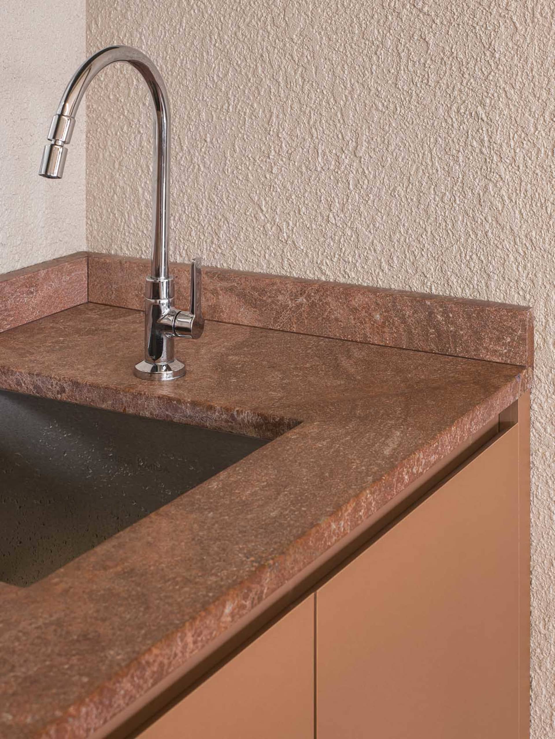 A bathroom with a marble sink and countertop, brown color scheme, and dim lighting