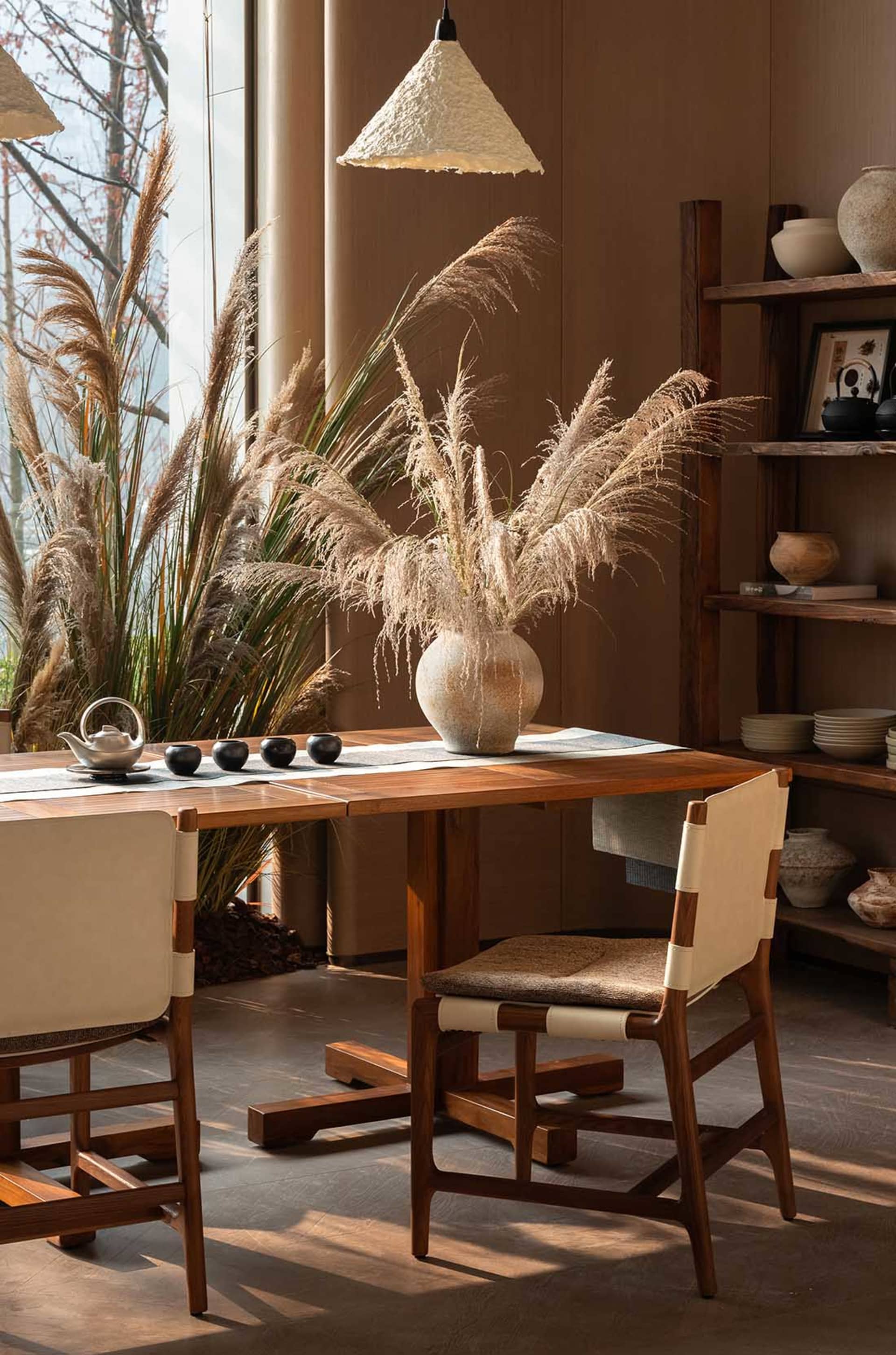 A well-lit dining room with a wooden table and chairs, surrounded by potted plants and a modern, minimalist aesthetic
