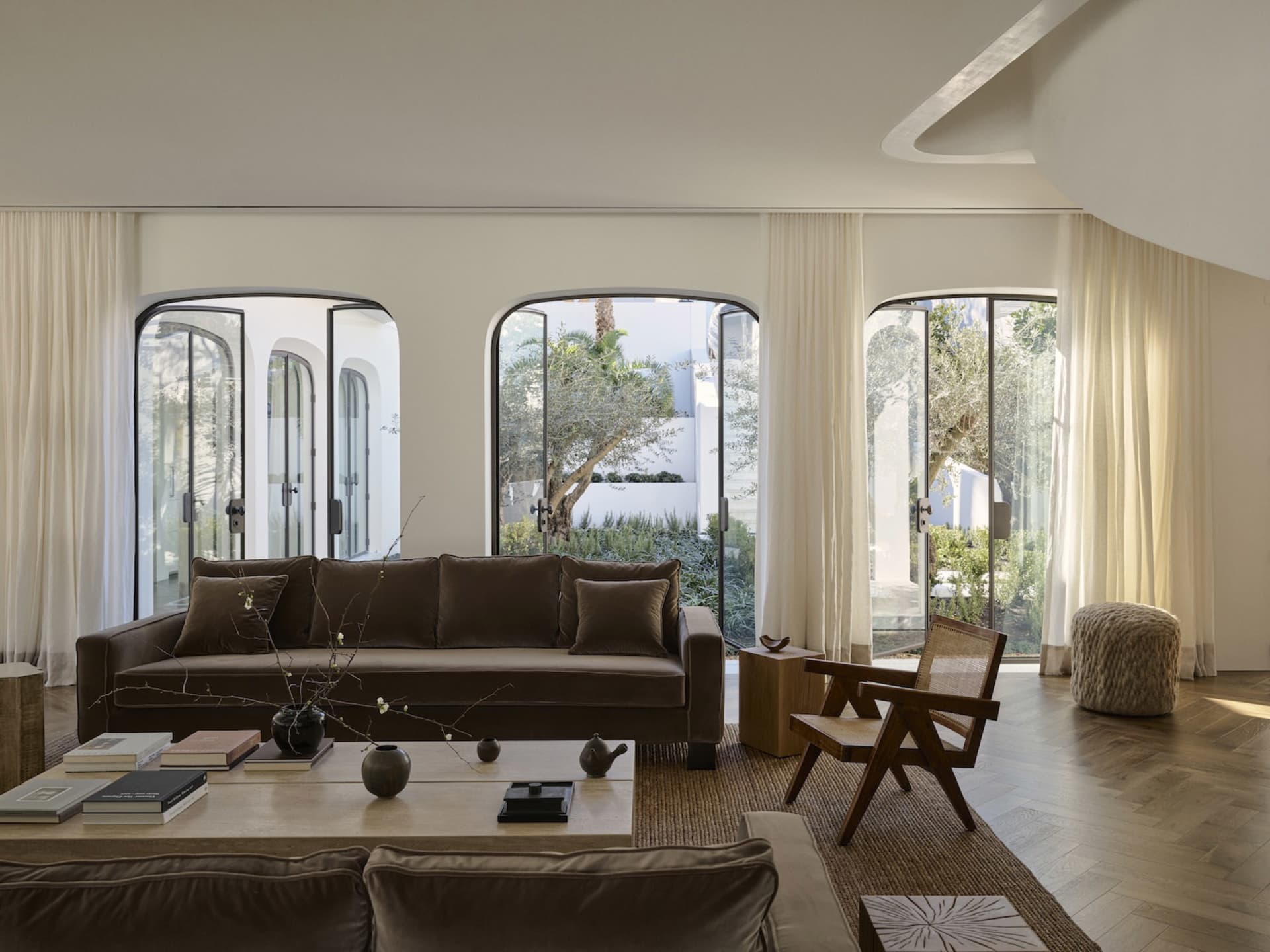 Cozy modern living space with brown furniture, potted plants, and natural light from windows