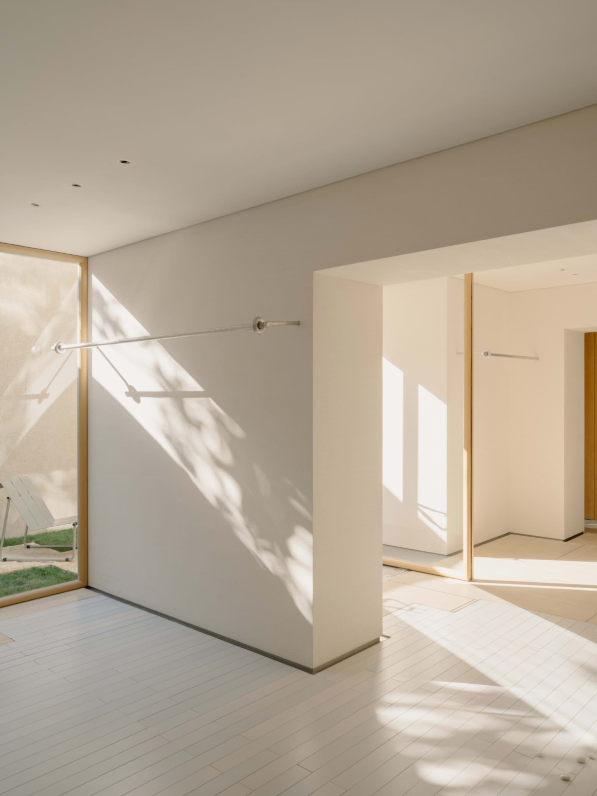 Bathroom with a white wall, a doorway, a shower, and a towel rack, lit by natural sunlight