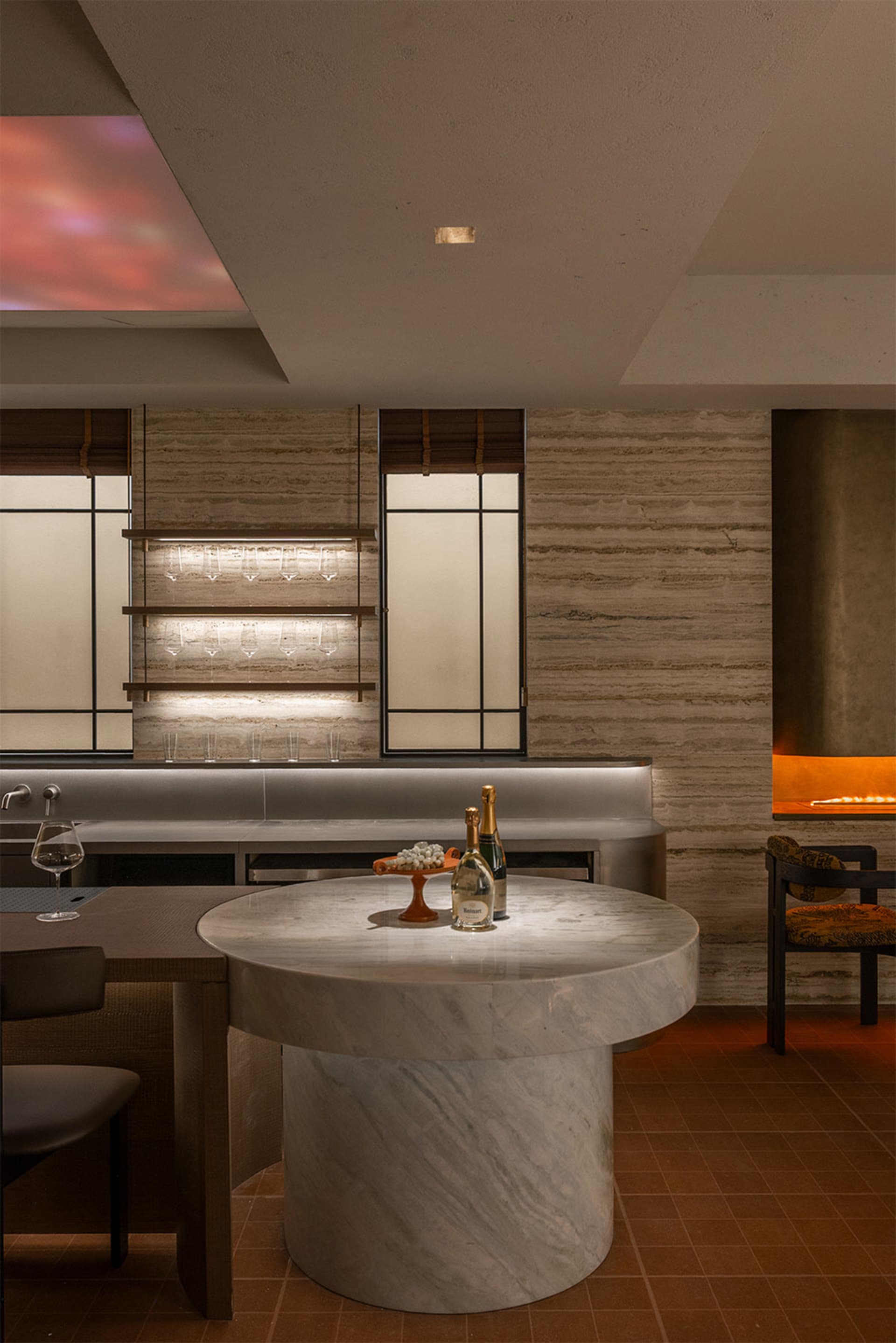 A dimly lit bar with a marble countertop, a wine bottle, and a wine glass, set in a modern restaurant or bar space