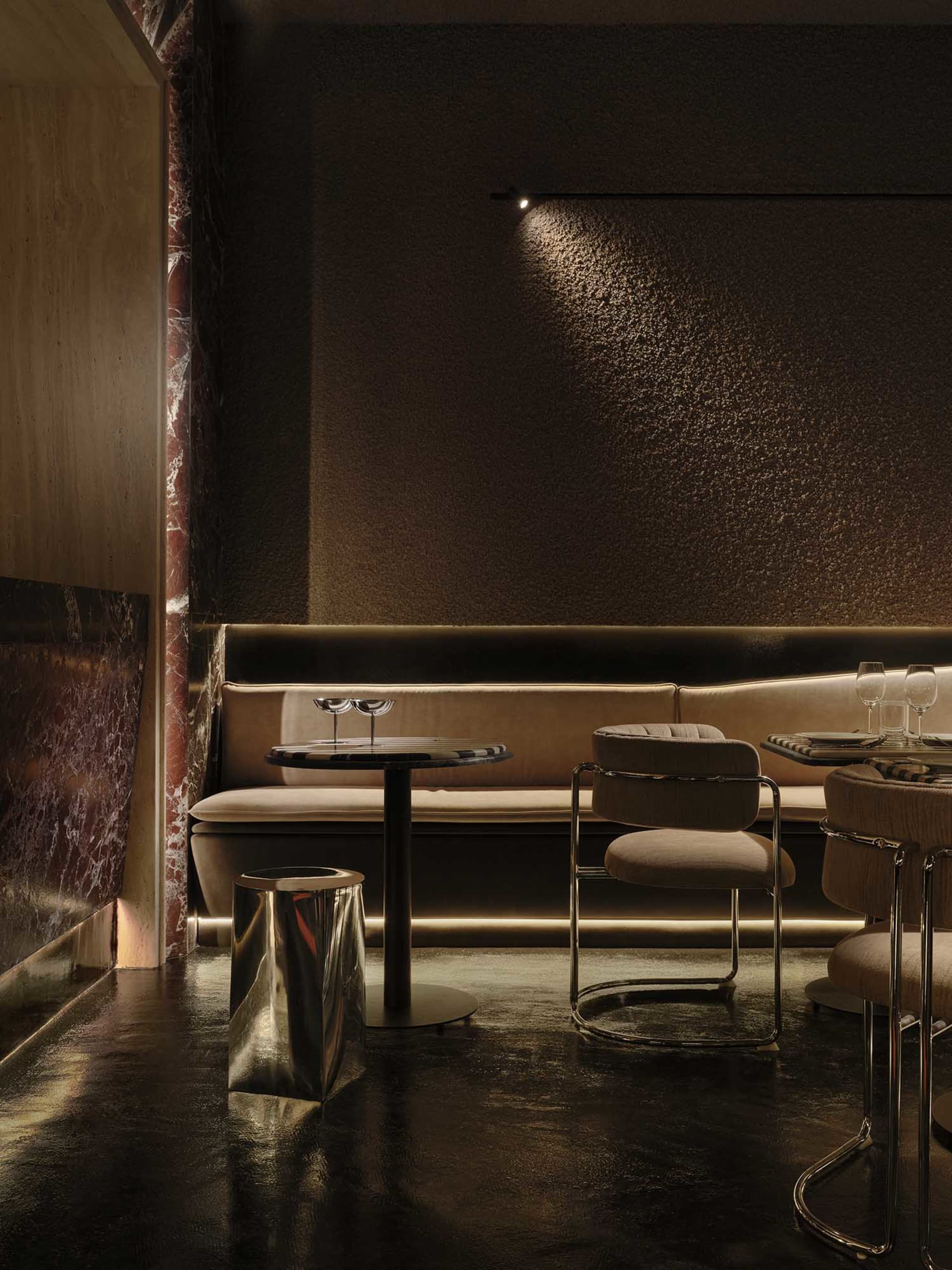 Dimly lit restaurant interior with a dining area, bar, and modern brown furniture, lit by overhead lamps