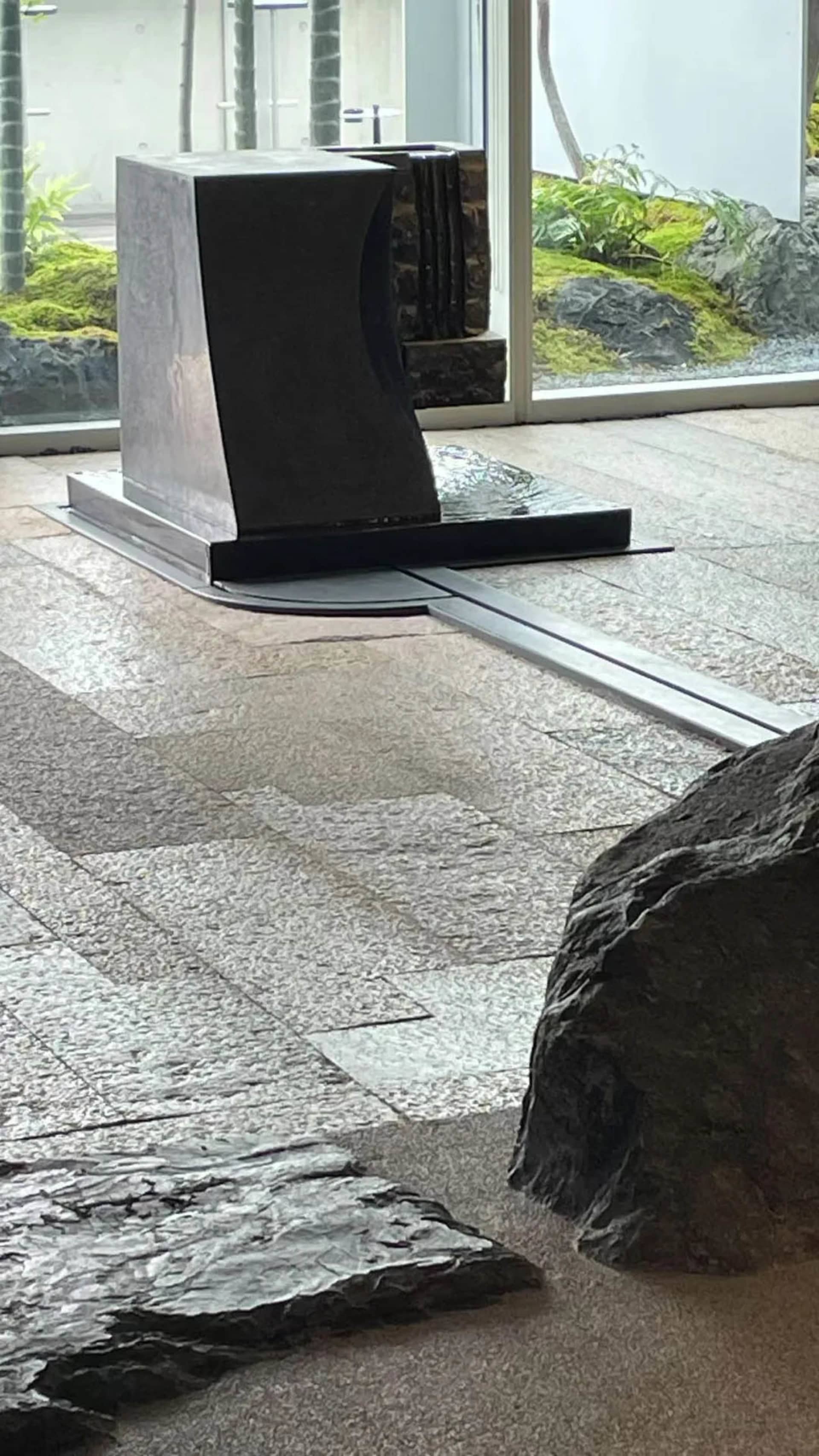 田園風格的客廳餐廳空間，牆壁為石頭，地板為石頭，角落有大石頭，低調照明營造出陰暗的氛圍