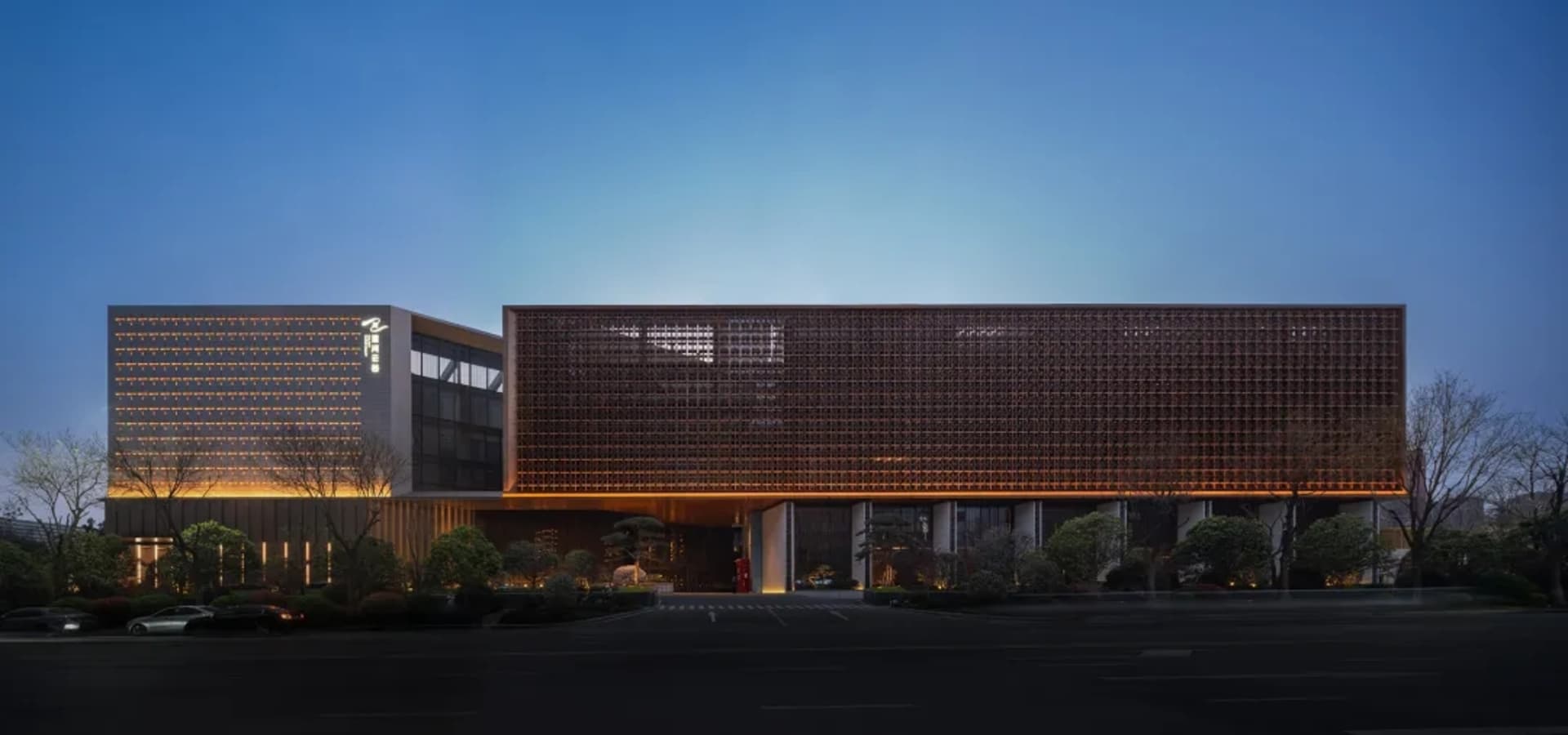 A modern-traditional building with a glass front, illuminated by natural light, featuring a mix of wood and glass materials