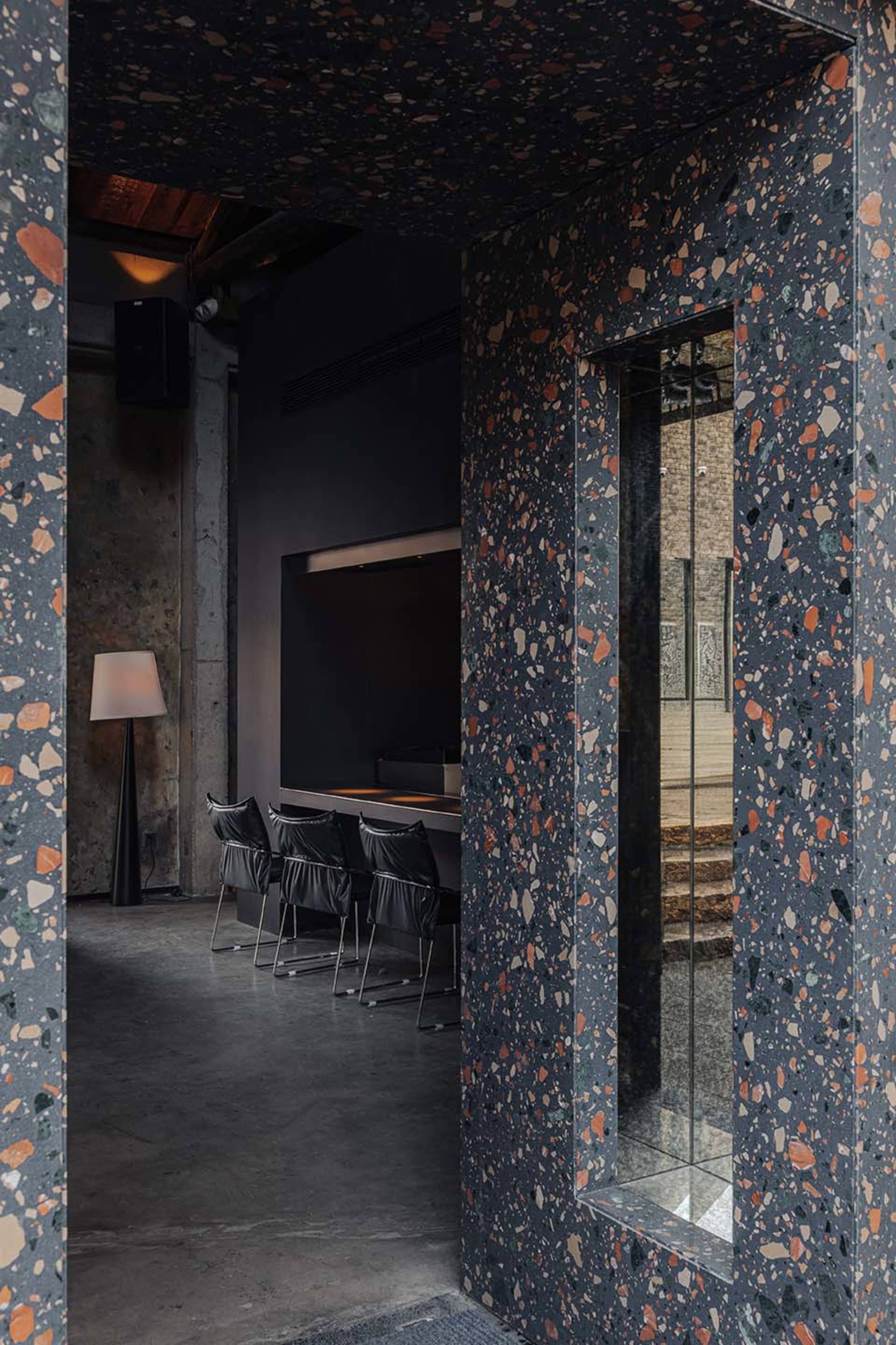Cozy modern dining space with a black wall, stone-like patterned wall, a dining table, and chairs, featuring a TV mounted on the wall