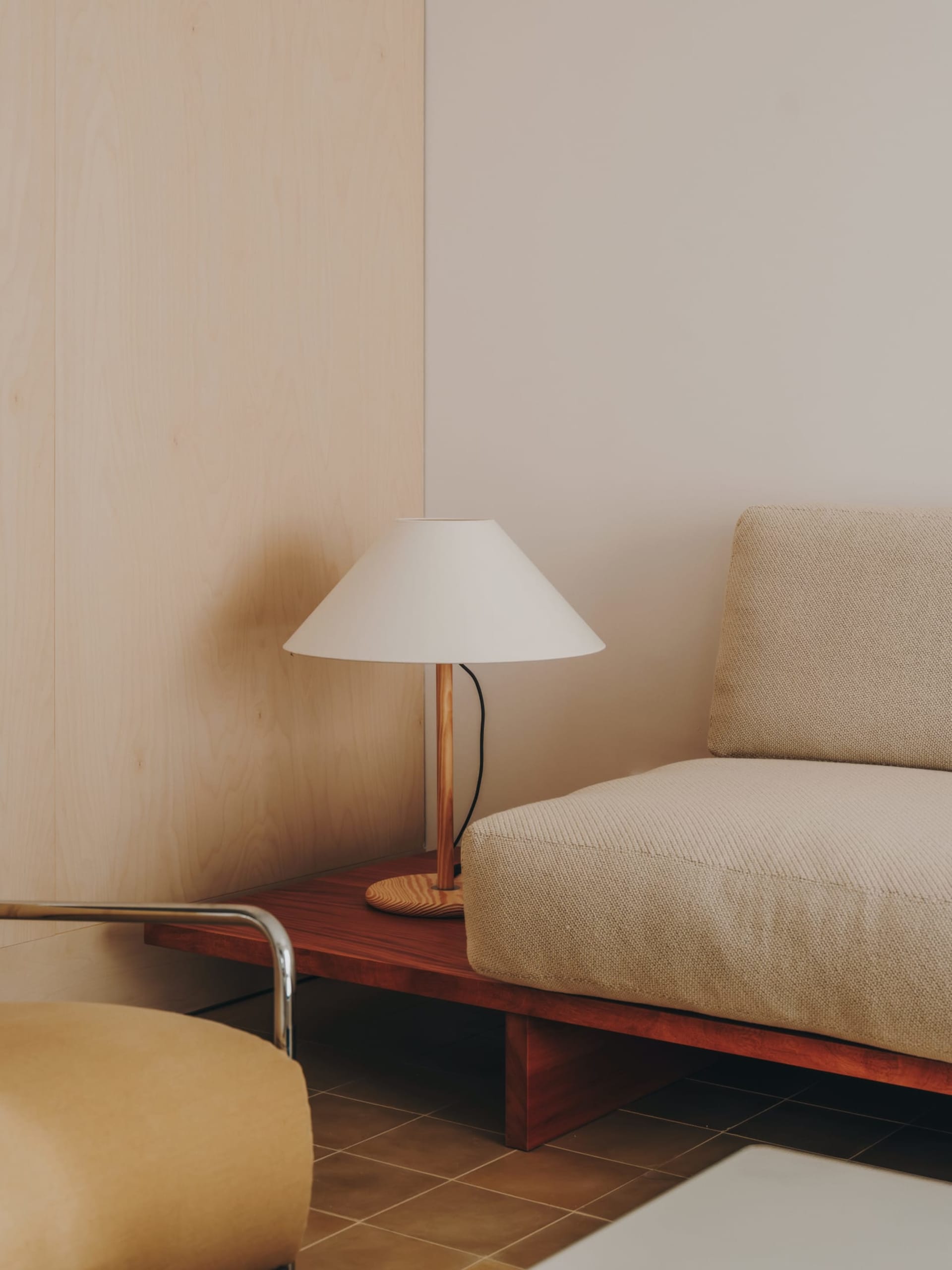 Cozy modern living space with a couch, chair, and lamp, featuring wood and fabric furniture in a well-lit room