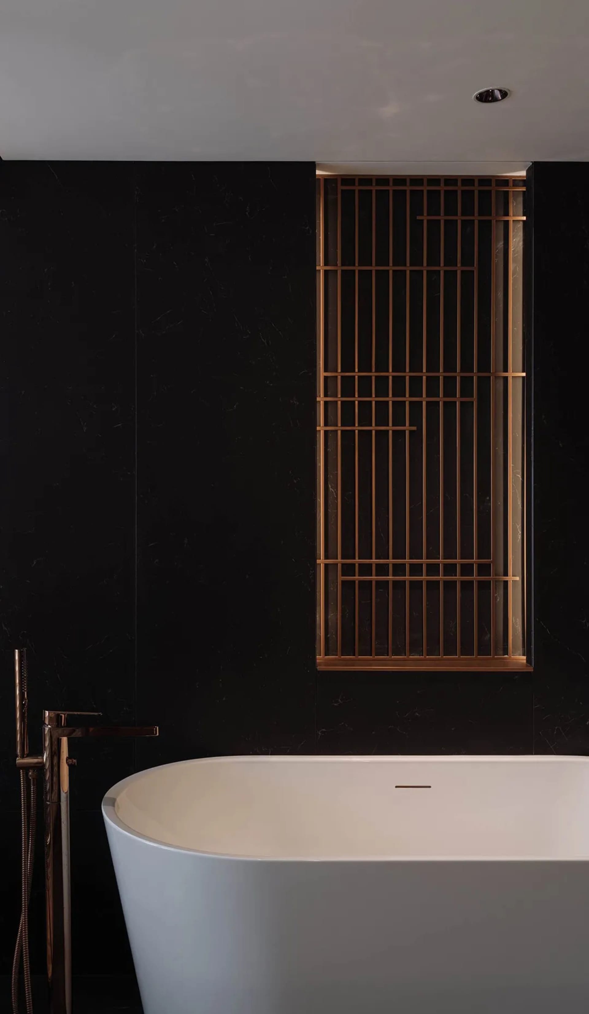 A modern bathroom with a white porcelain bathtub and a black wall, featuring natural light from an open window