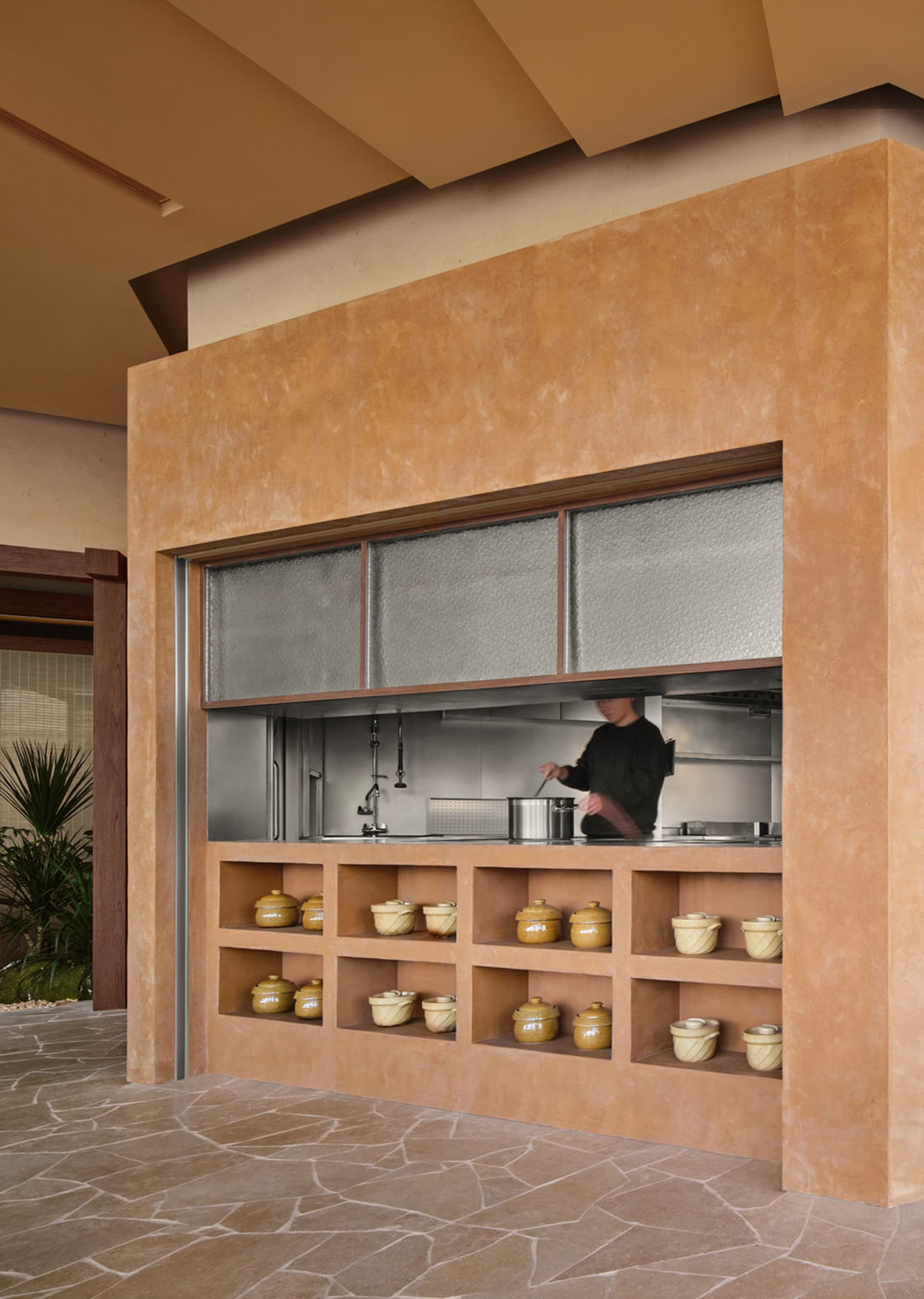 A warm and inviting kitchen with a man preparing food, stainless steel appliances, and multiple bowls on a counter