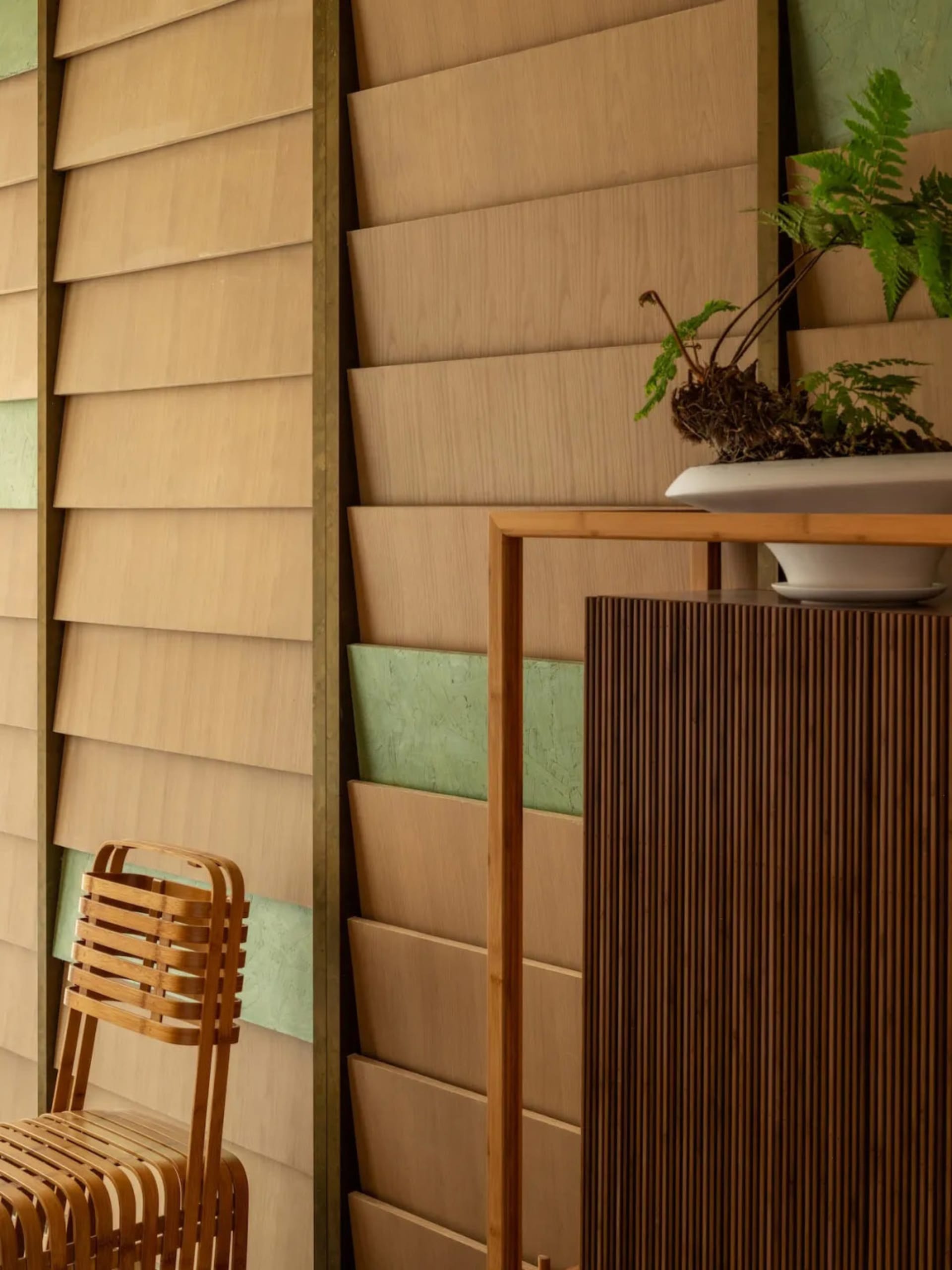 Warm and inviting living space with wooden walls, a wooden chair, and a potted plant on a shelf