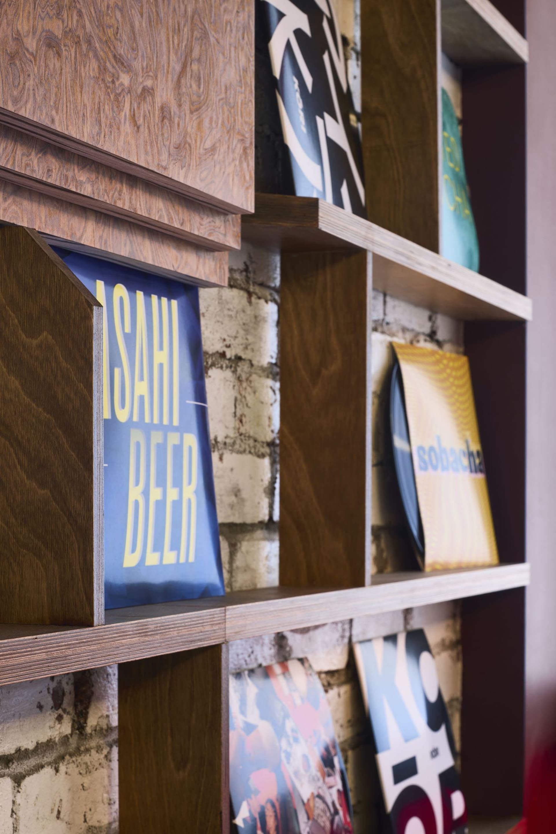 A wooden bookshelf filled with various books of different sizes, arranged in a cozy and organized space, likely a home library or bookstore