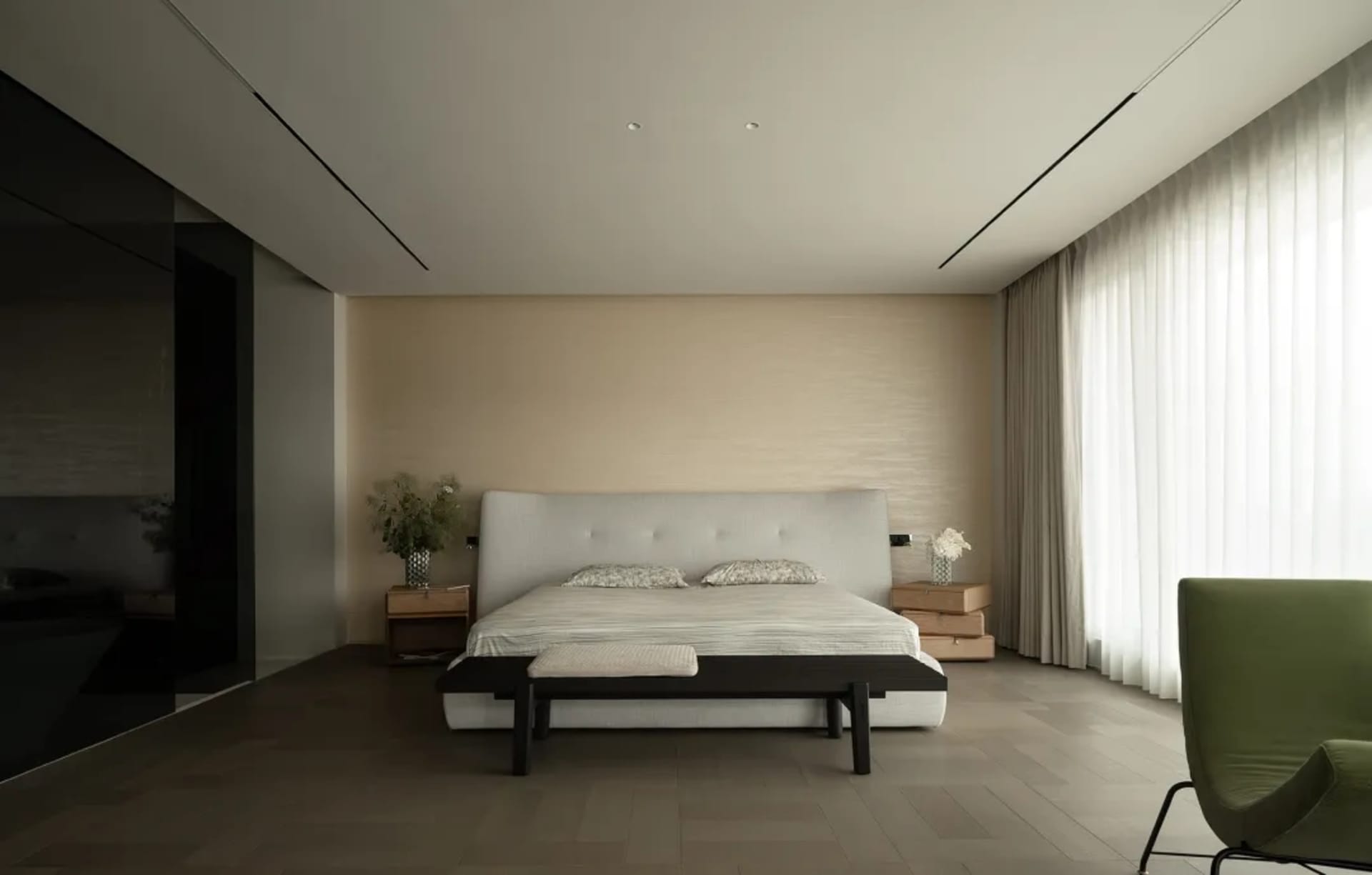 A well-lit modern bedroom with a white bed, black frame, and a nightstand with a vase on top, set against a clean background