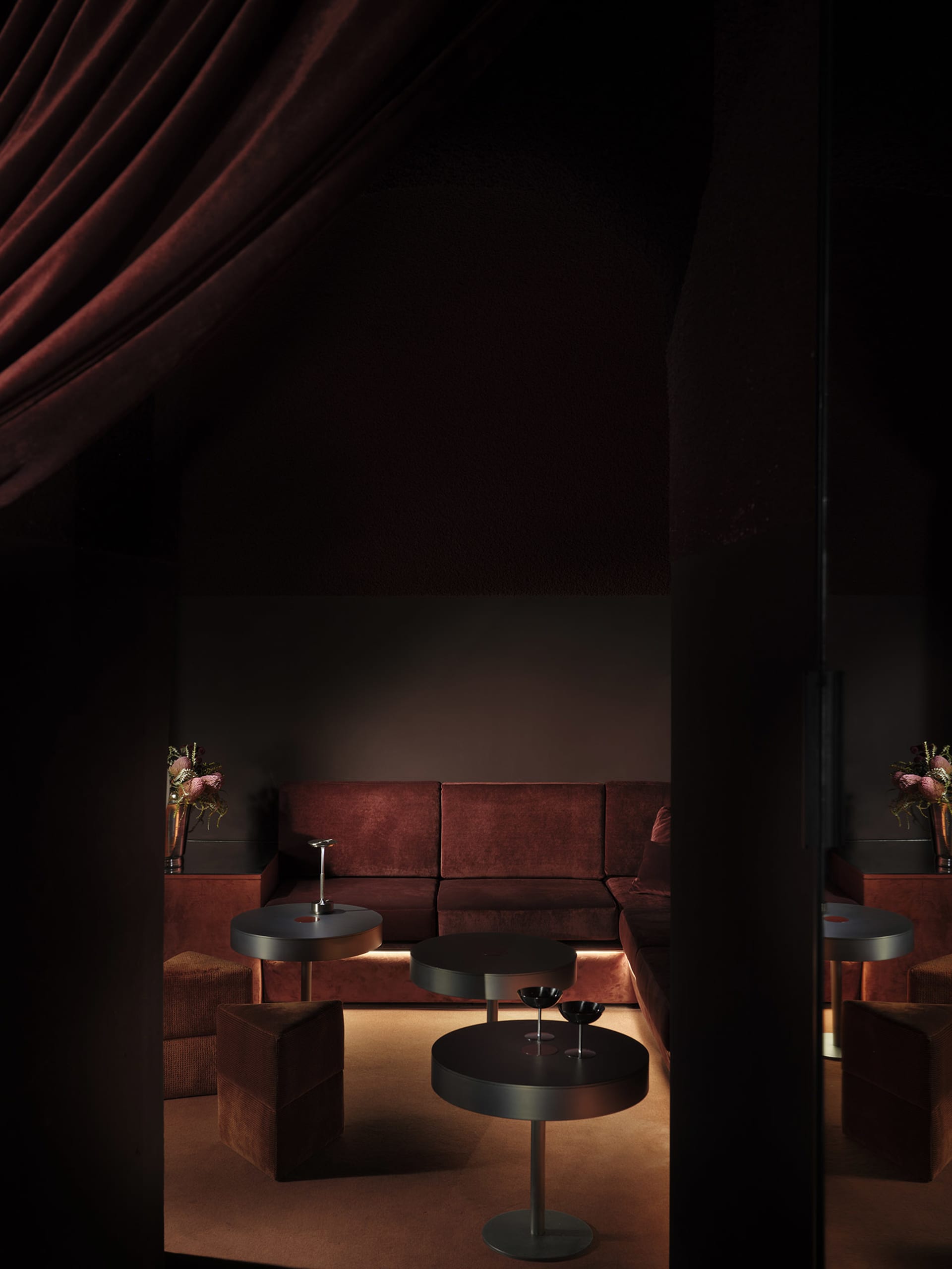 Cozy living room with brown furniture, a red curtain, and dim lighting