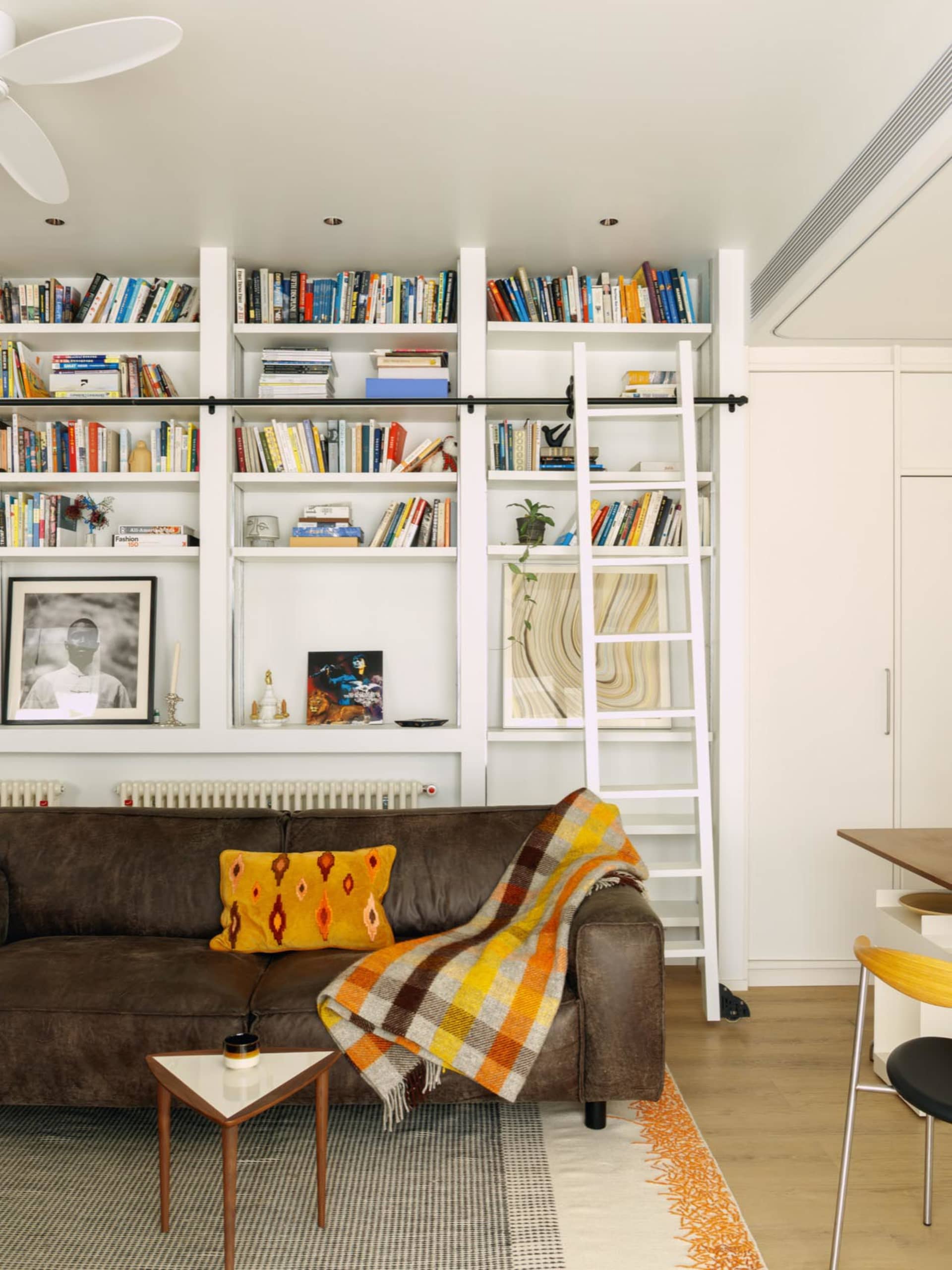 Cozy modern living space with a couch, chair, dining table, and bookshelf, decorated with books and featuring a modern and comfortable style