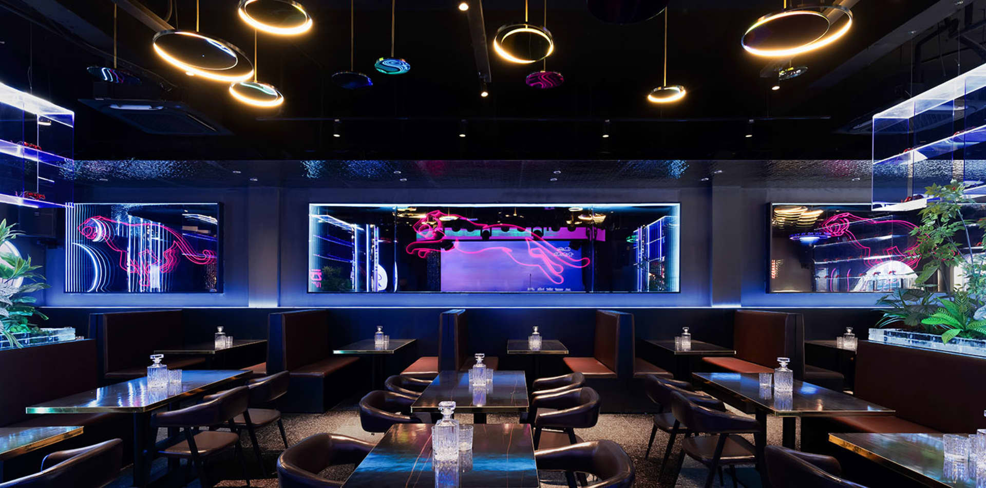 Elegant restaurant interior with black and purple decor, wine glasses, and dim lighting
