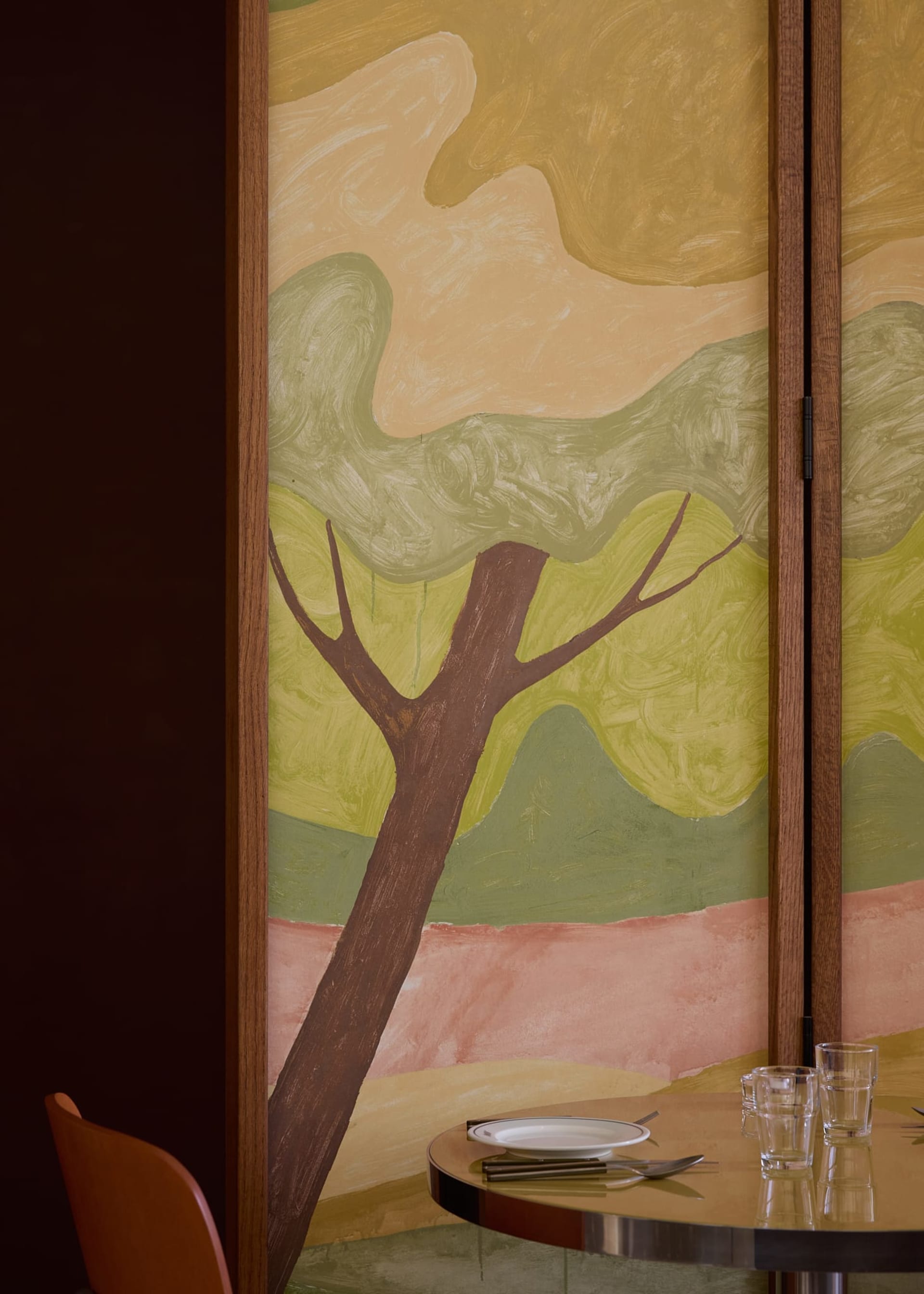 Impressionist painting of a tree in a forest, set in a brown wooden frame, with warm and inviting lighting