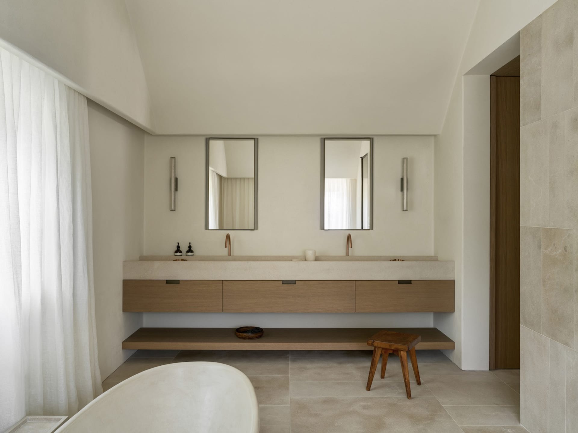 Bathroom with a white bathtub, wooden vanity, and dim lighting, creating a cozy and relaxing atmosphere