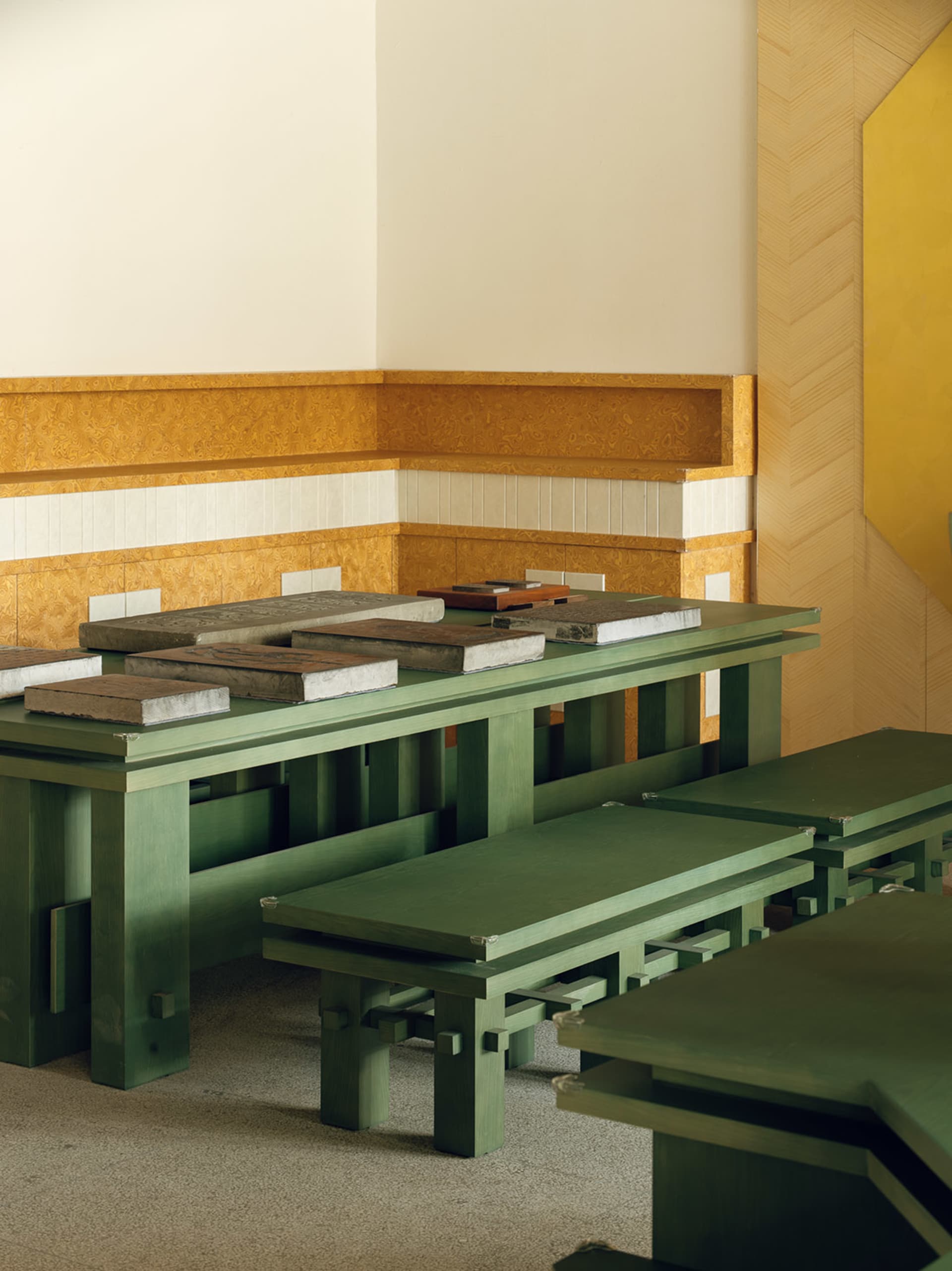 A modern dining space with a wooden table surrounded by metal benches, well-lit and inviting