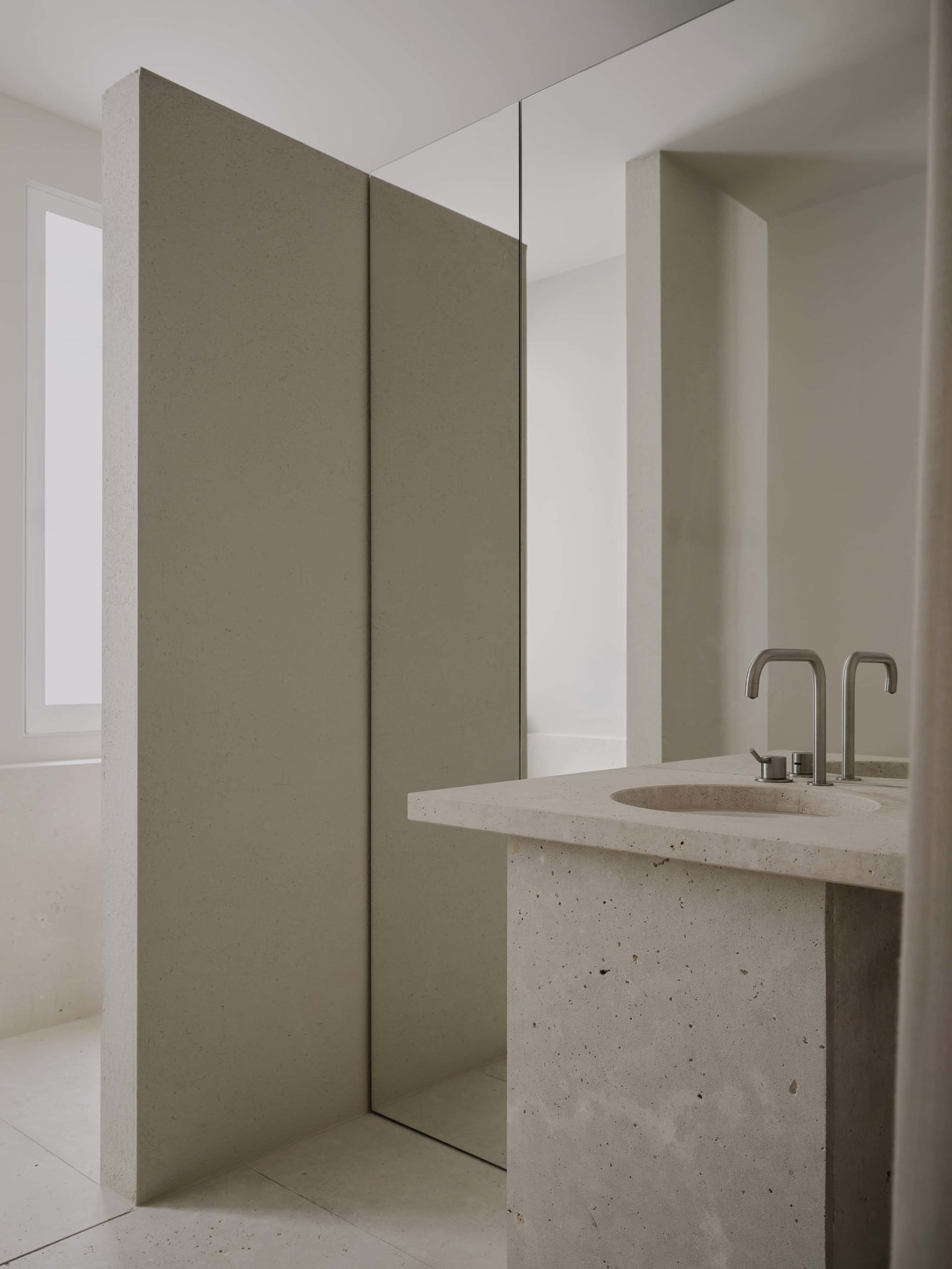 Modern bathroom with a marble sink, shower, and mirror, in a clean and well-maintained space