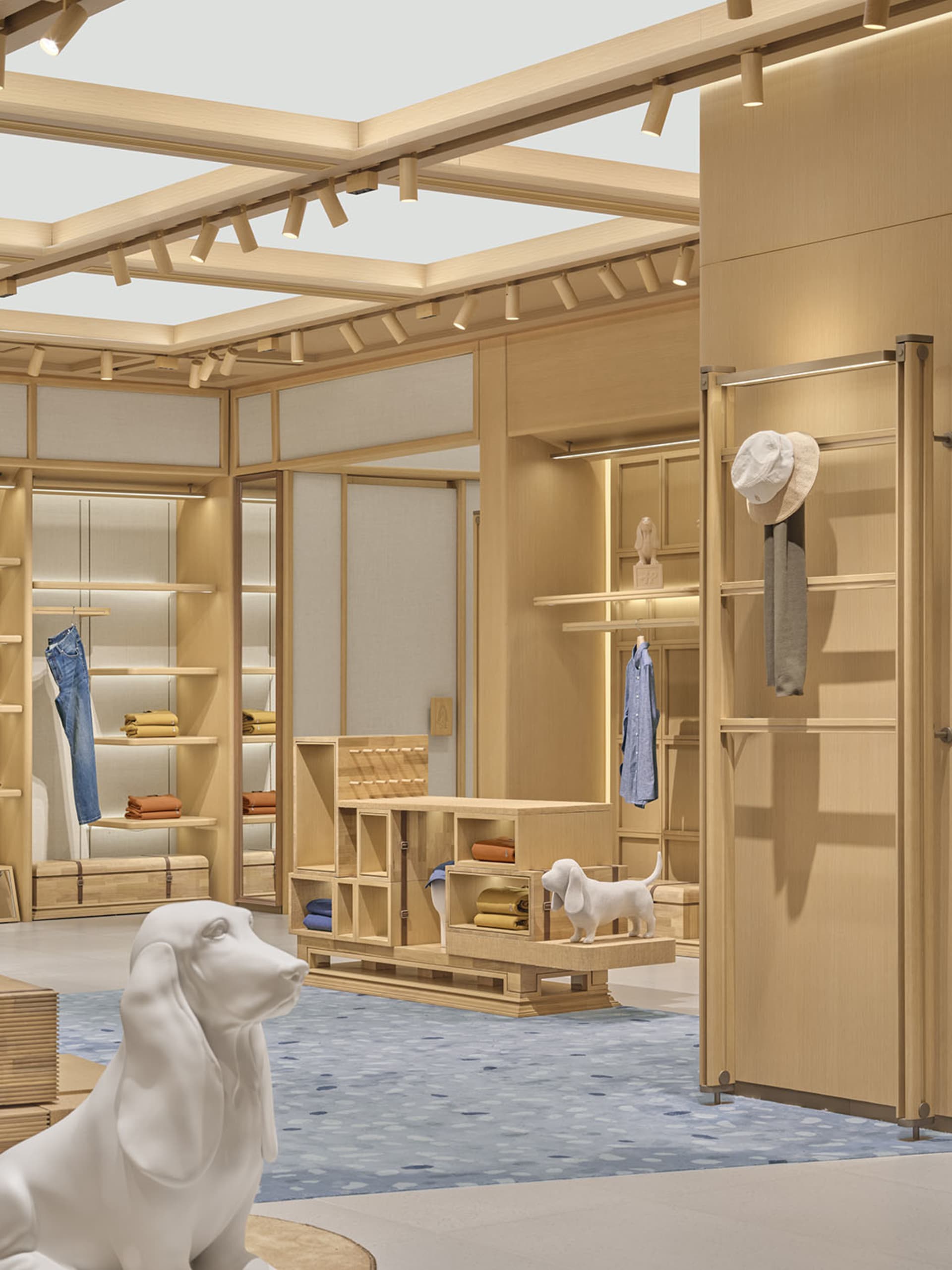A casual clothing store with a wooden floor, filled with shirts and hats, and a dog sitting in the middle