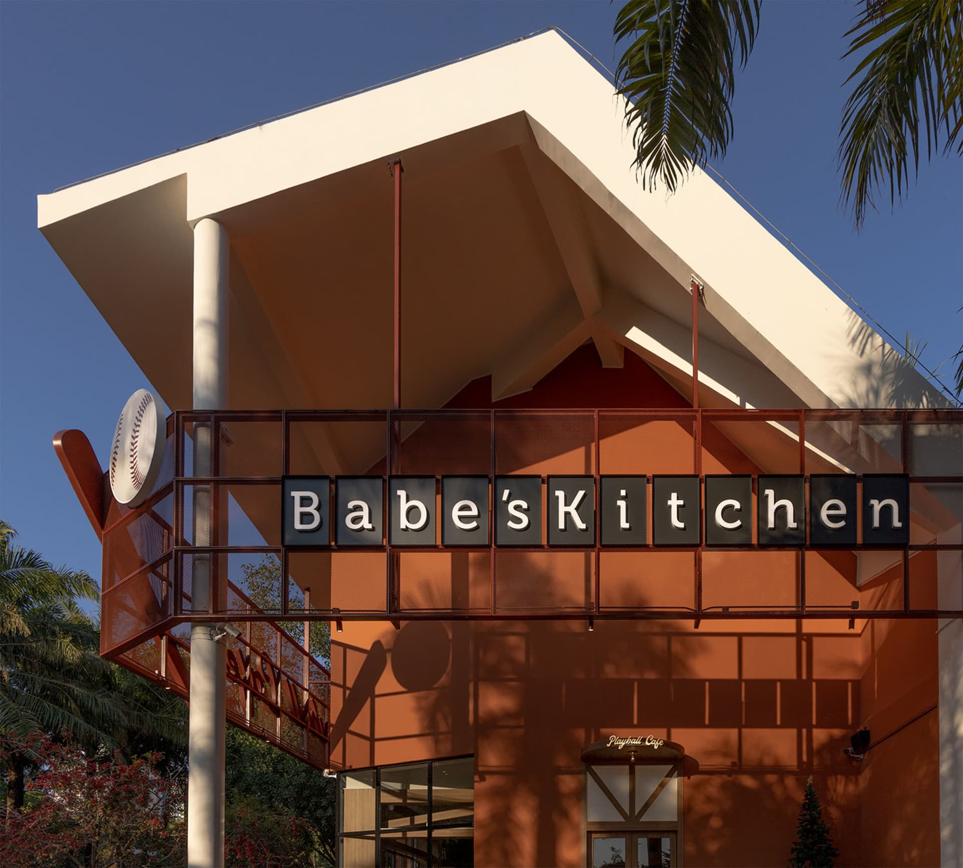 A casual restaurant with a modern architectural style, featuring a red roof, orange and white colors, and a dining table and chairs in a warm and inviting space with natural light