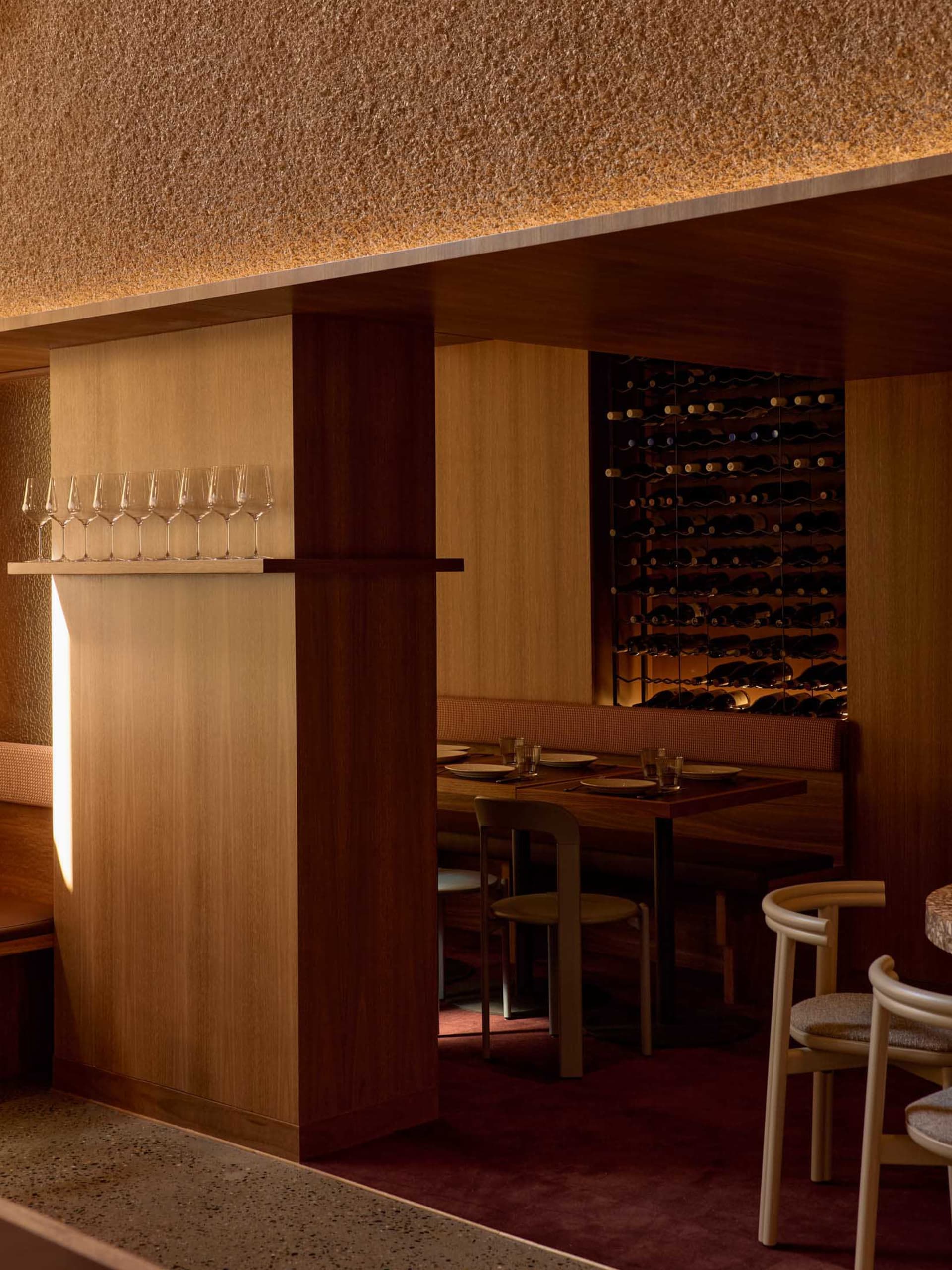 Cozy modern dining space with a long wooden table, wine glasses, and dim lighting