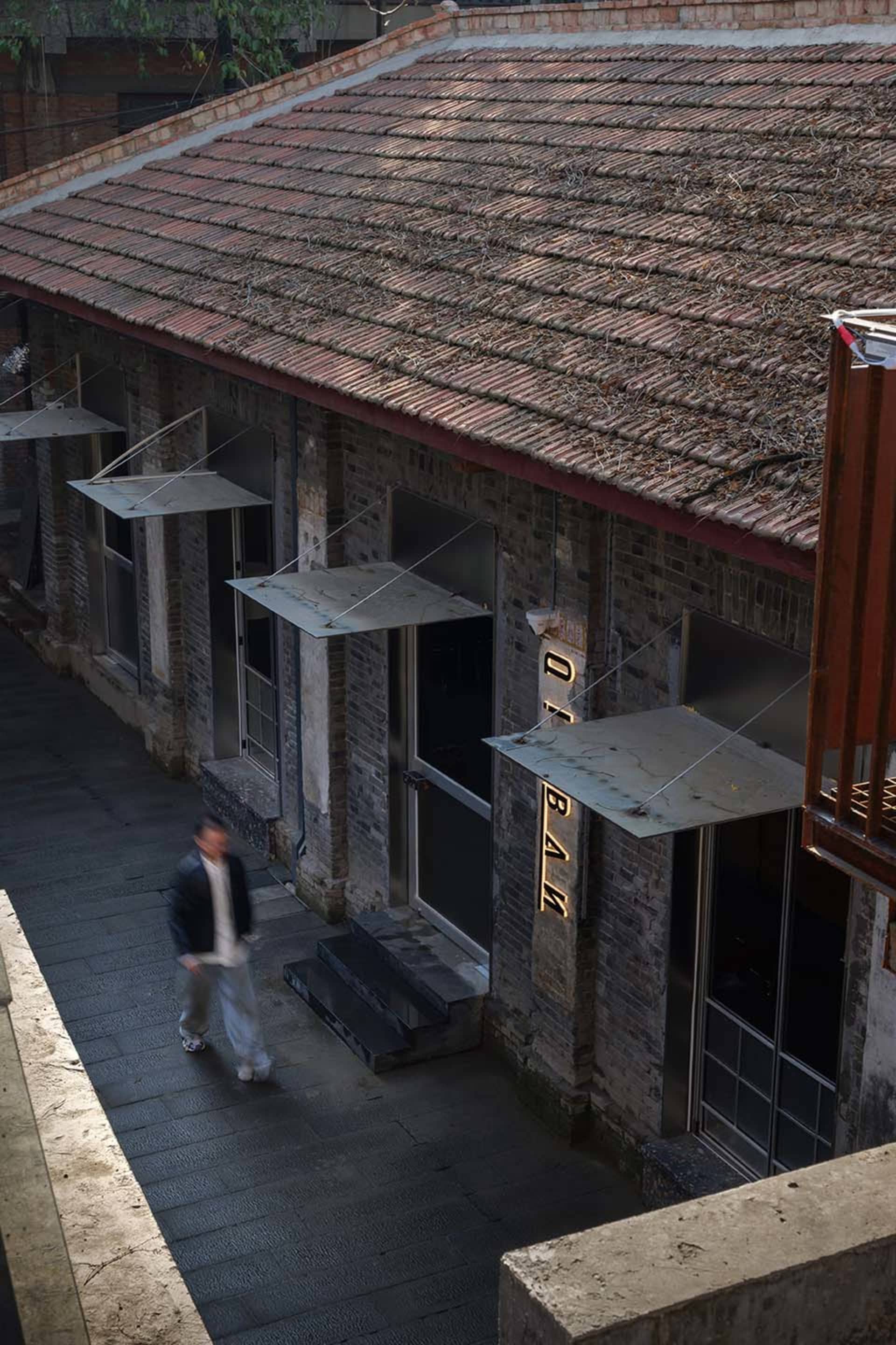 一座紅磚屋頂的建築，前面有個男人走過，建築置於城市環境中，混合多種建築風格的場景