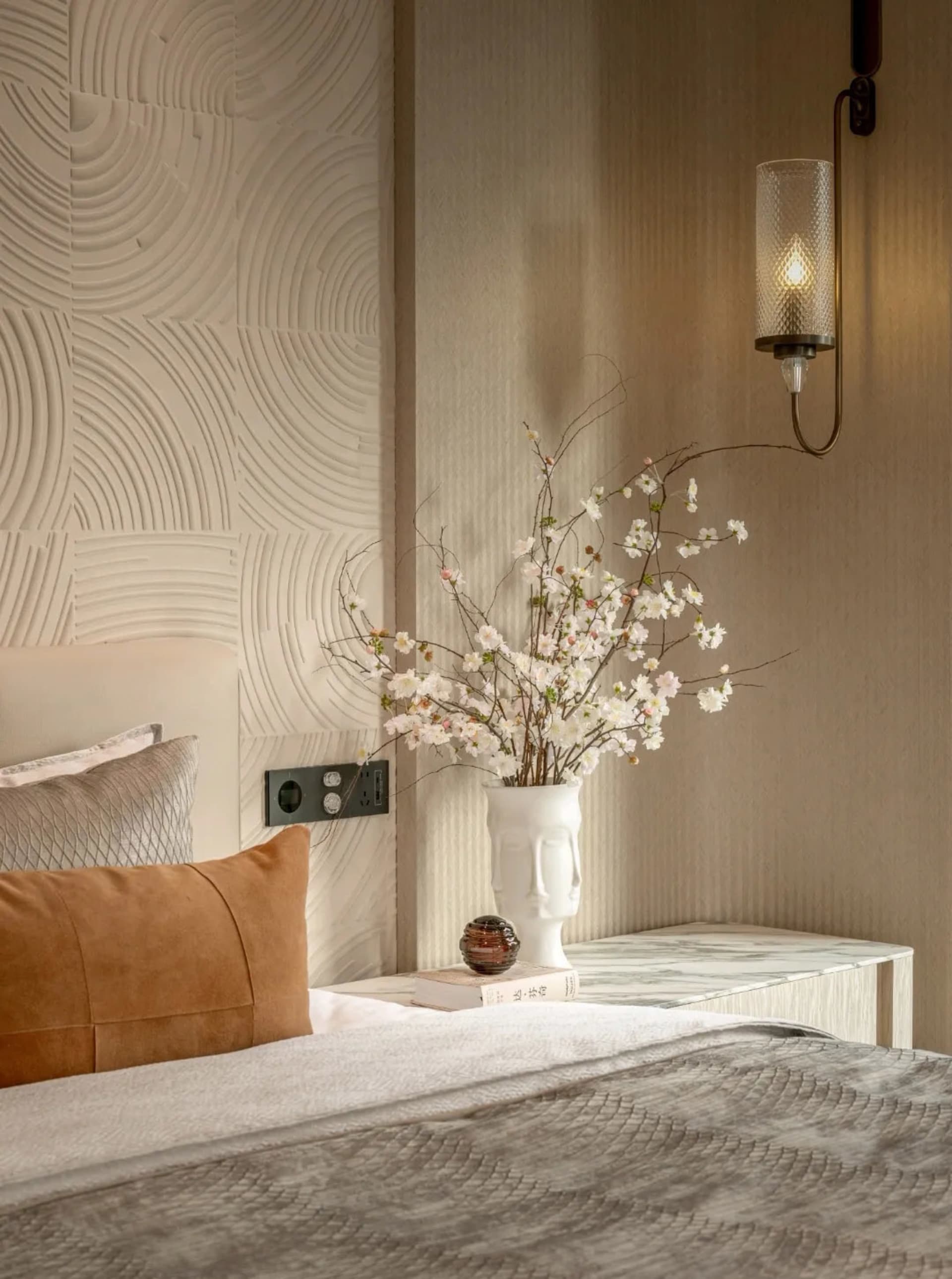 Cozy bedroom with a bed, nightstand, and vase with flowers on a patterned wallpaper background