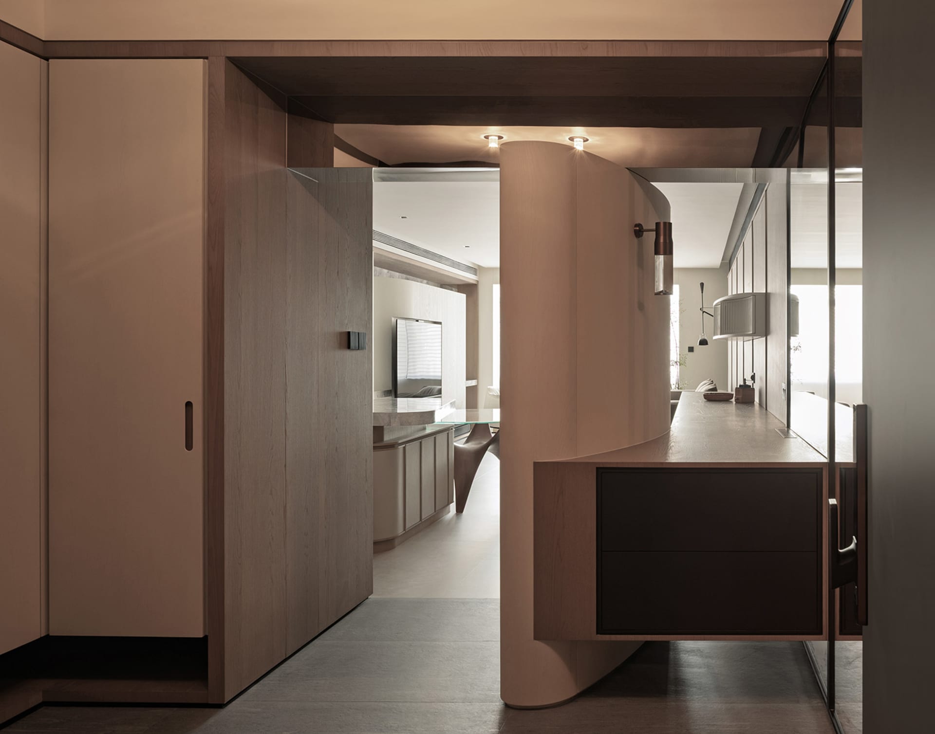 A well-lit modern room with a wooden floor, a glass door, a kitchen area with a sink and dining table, and a TV, creating a warm and inviting atmosphere